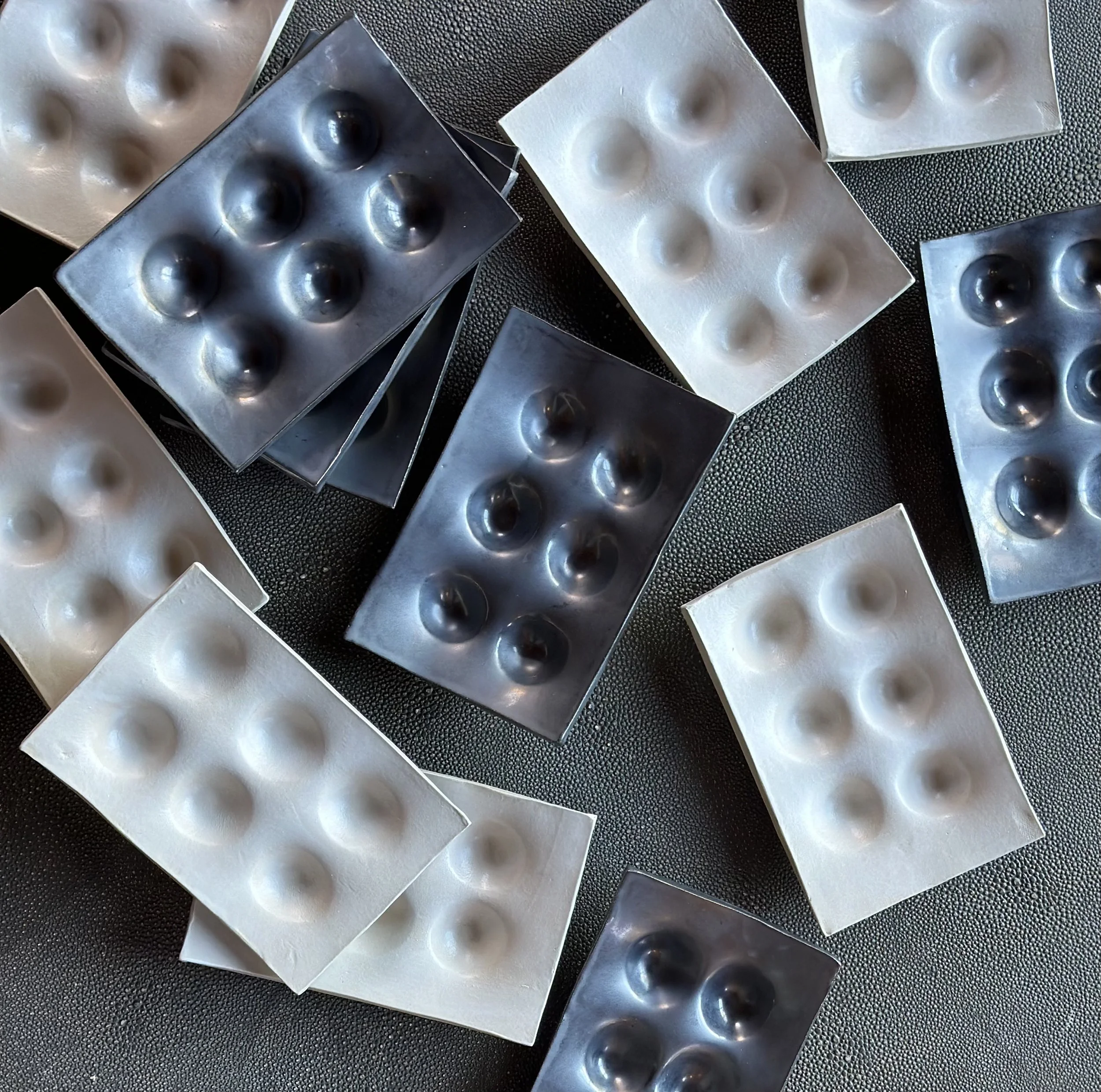 Multiple blister packs of black and white pills laid out on a dark surface.