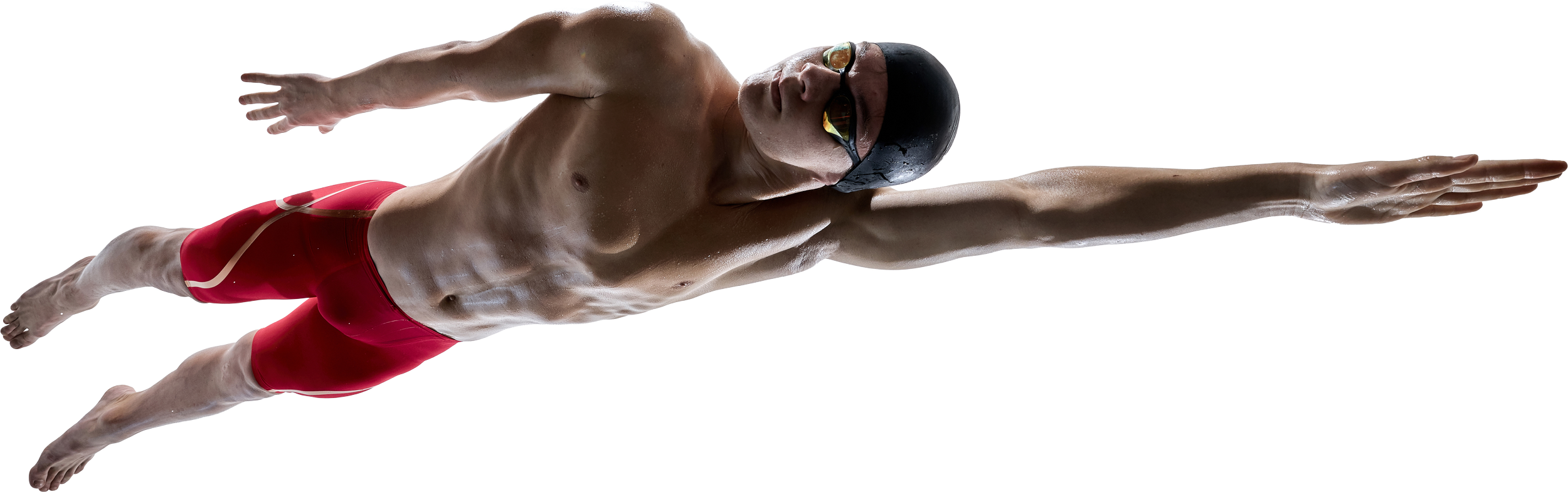 Male swimmer in a streamlined diving pose wearing red swim trunks and goggles.