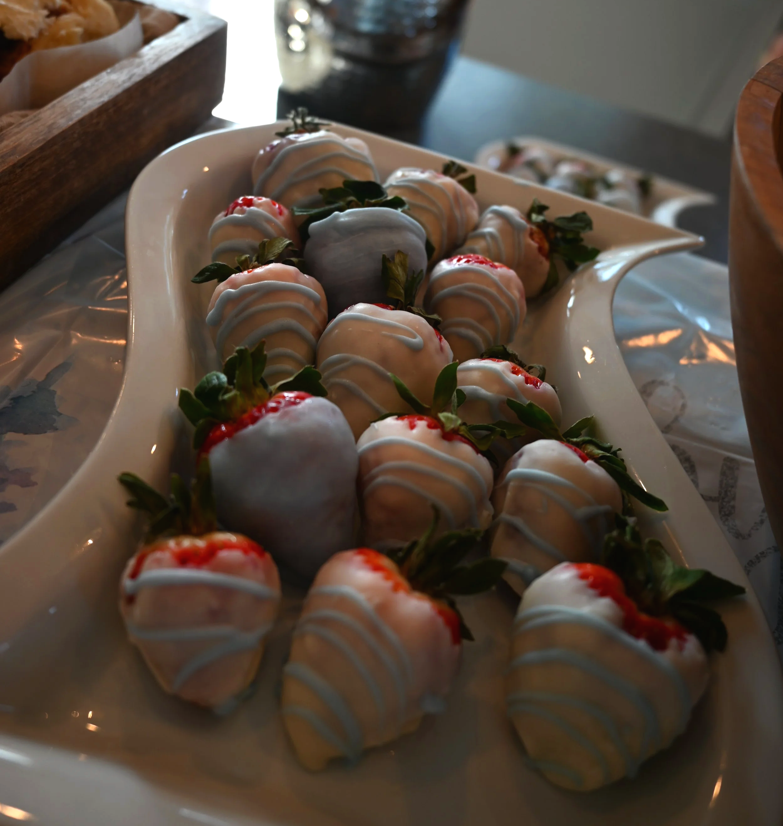 White chocolate covered strawberries with drizzle on a decorative platter.