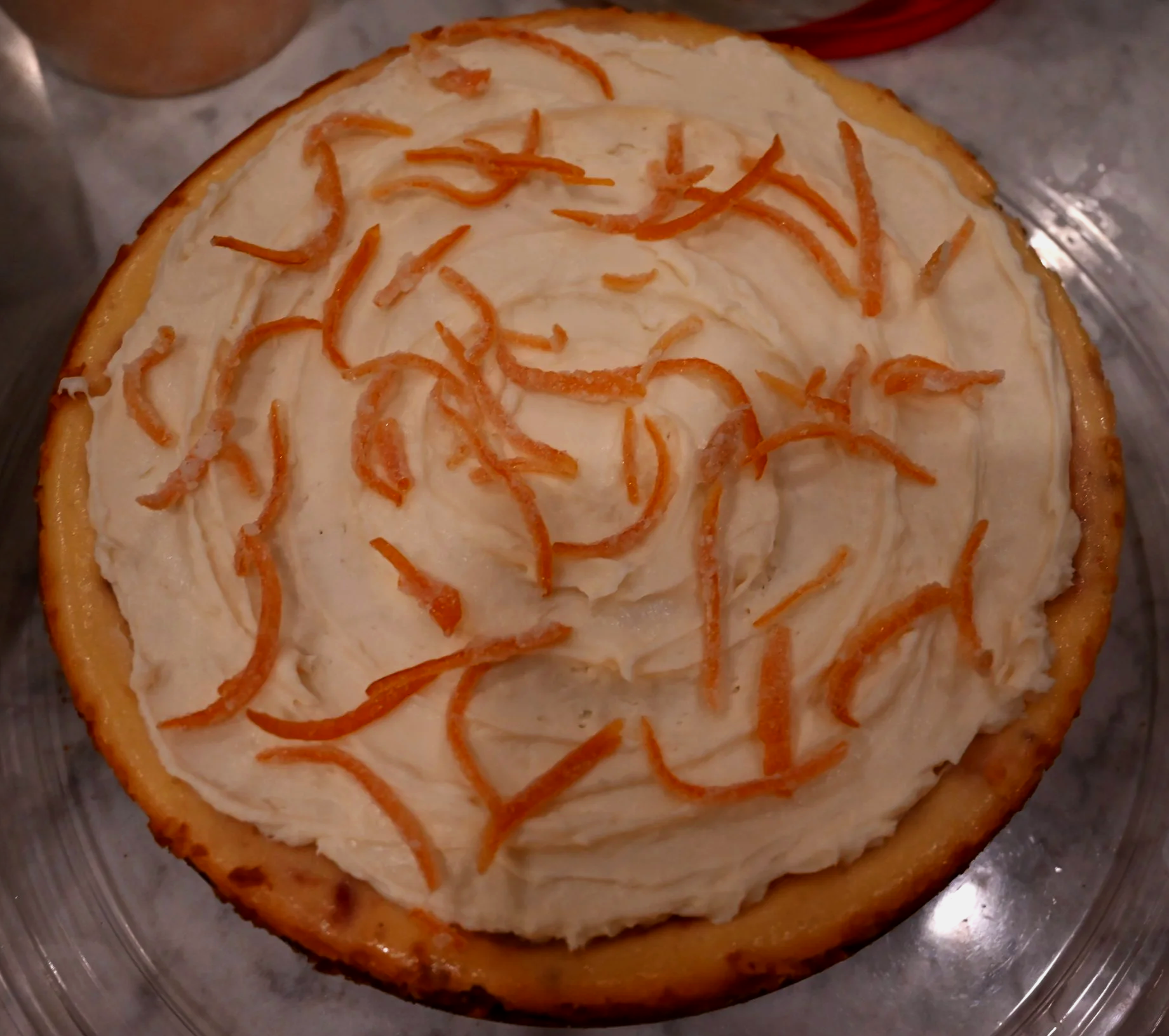 Cheesecake with whipped cream and shredded orange zest on top.