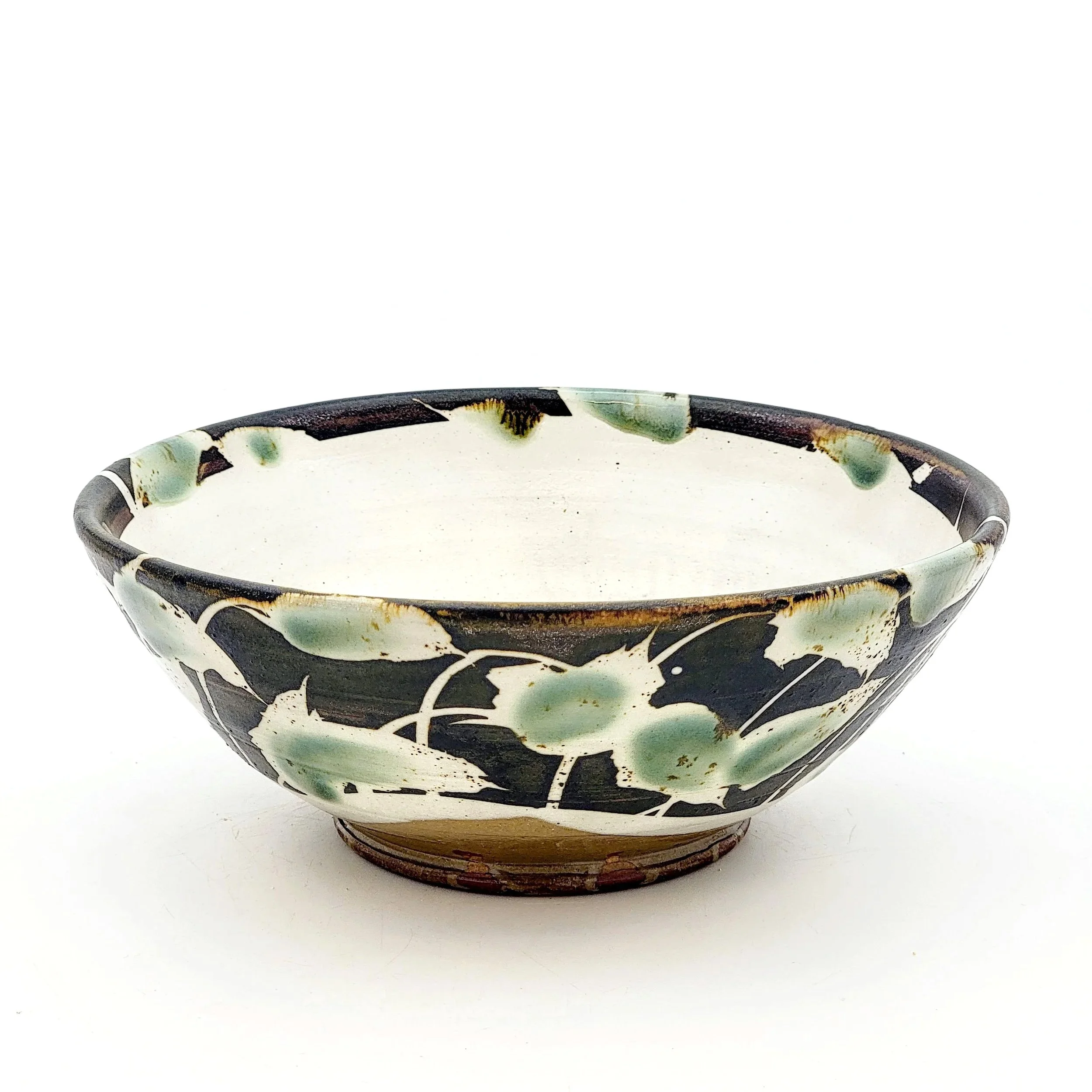 Decorative ceramic bowl with a floral pattern in black, white, and green, set against a white background.