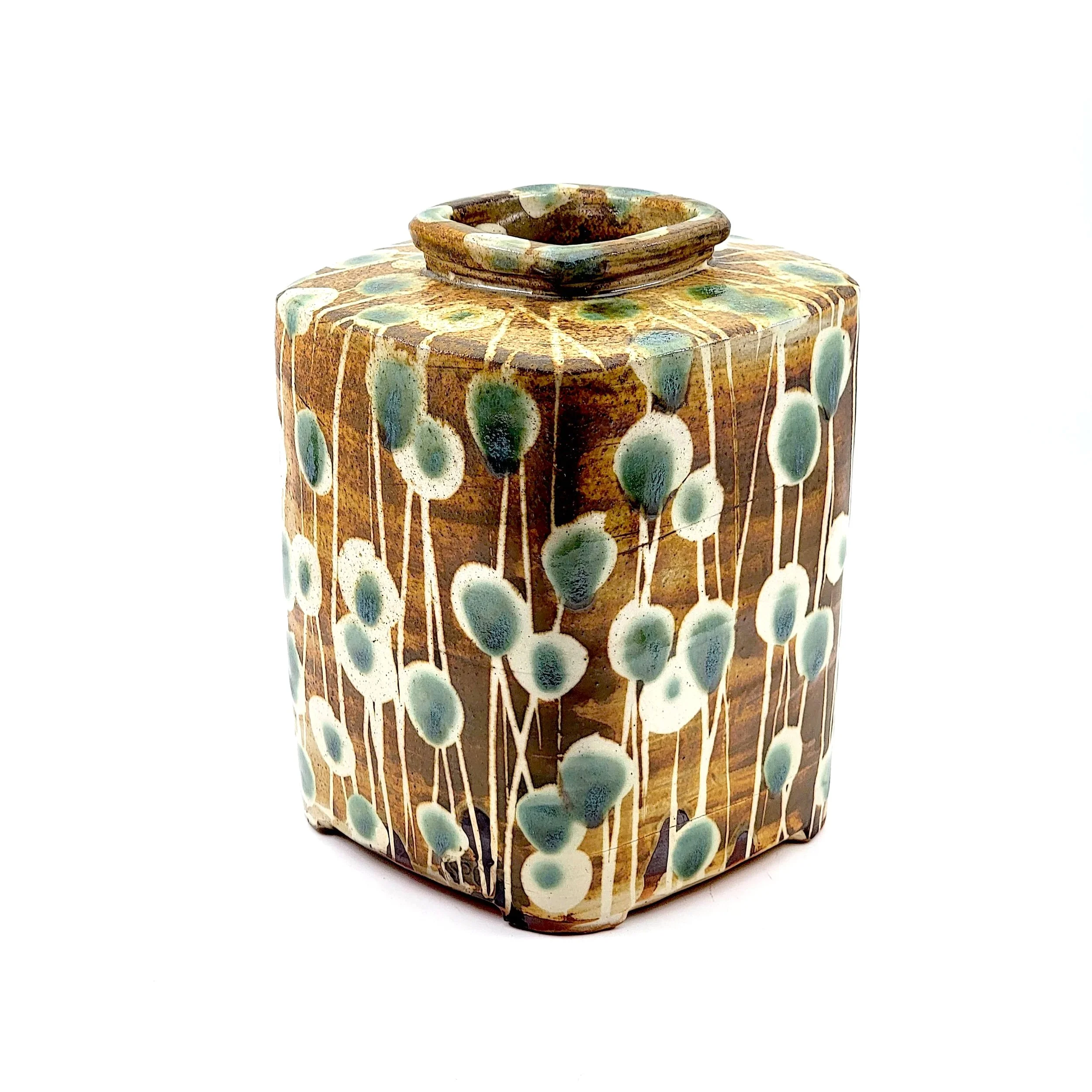 Colorful ceramic vase with a square shape, decorated with a pattern of white and green dots on a brown background, with a square opening at the top.
