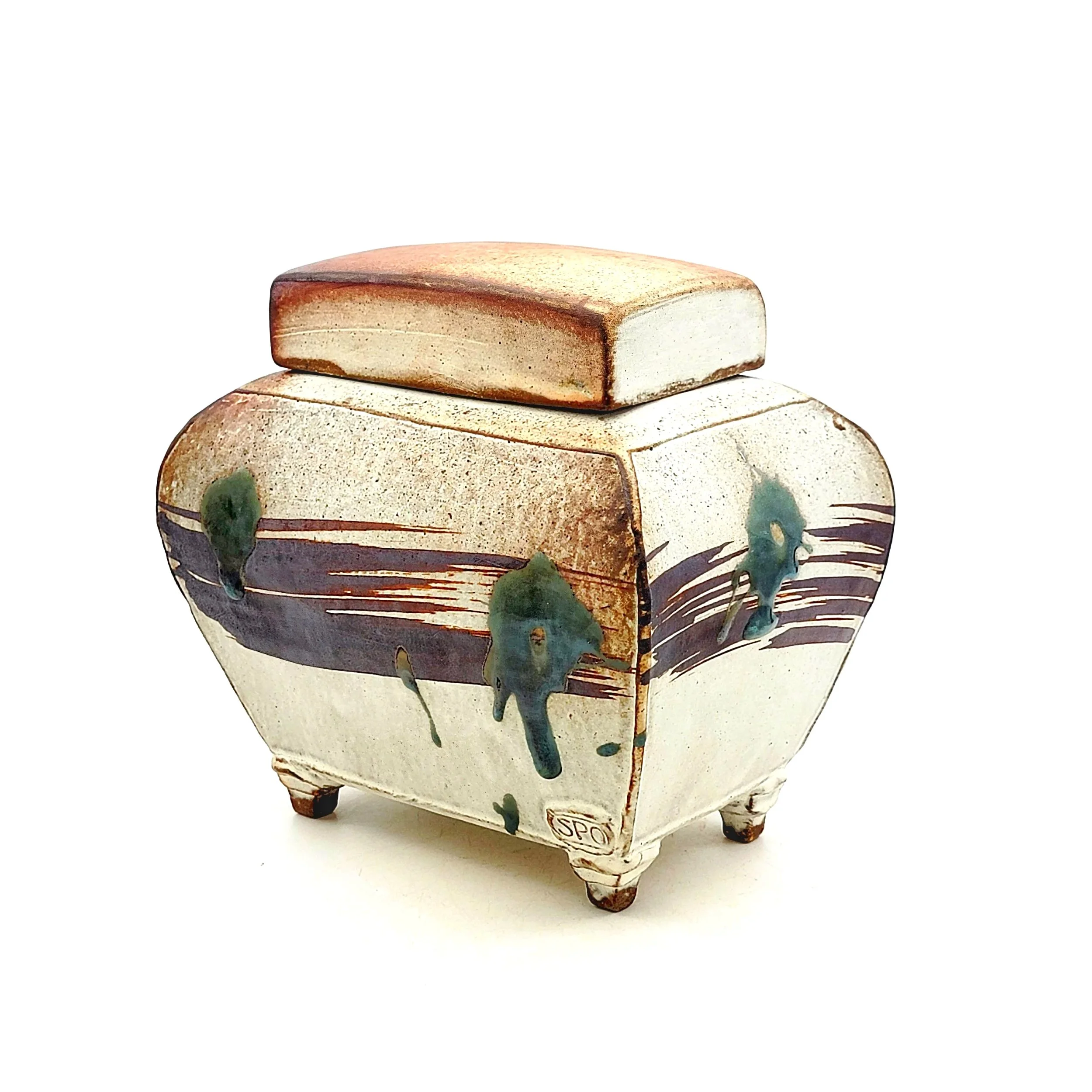 A small, decorative ceramic box with a lid, featuring abstract painted brush strokes and greenish-blue drips on a cream-colored surface, sitting on four legs.