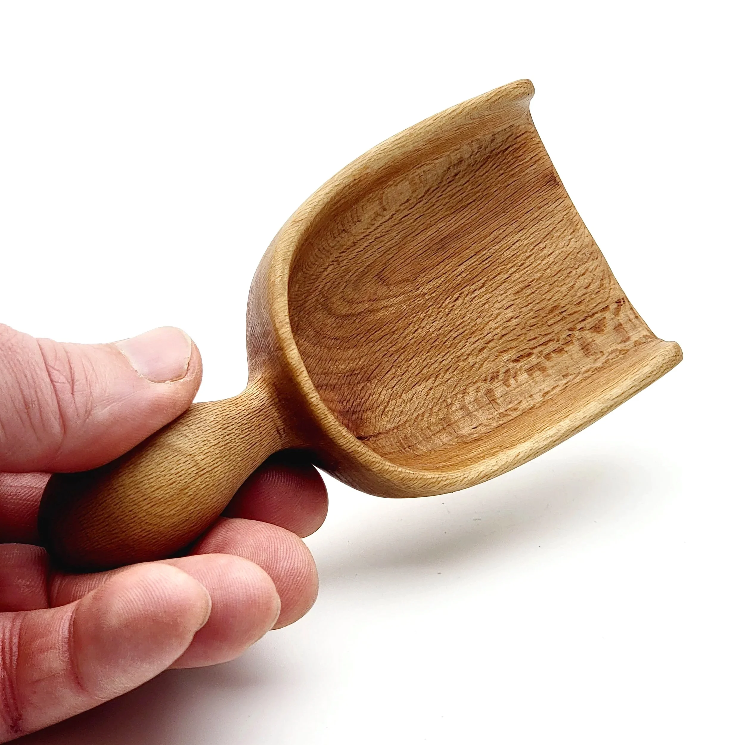 Hand holding a small wooden scoop against a white background.
