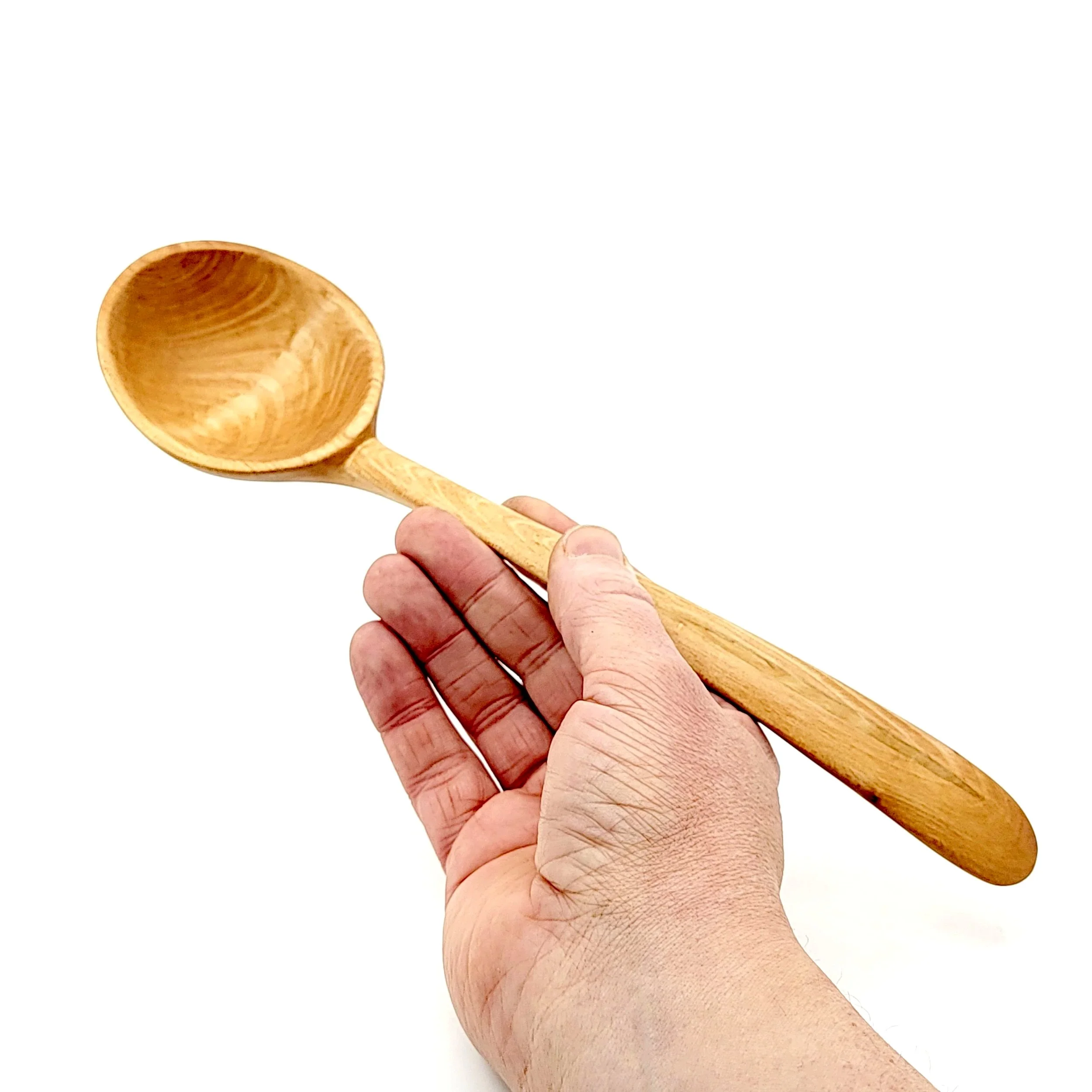 A hand holding a wooden spoon with a rounded bowl and a long handle against a white background.