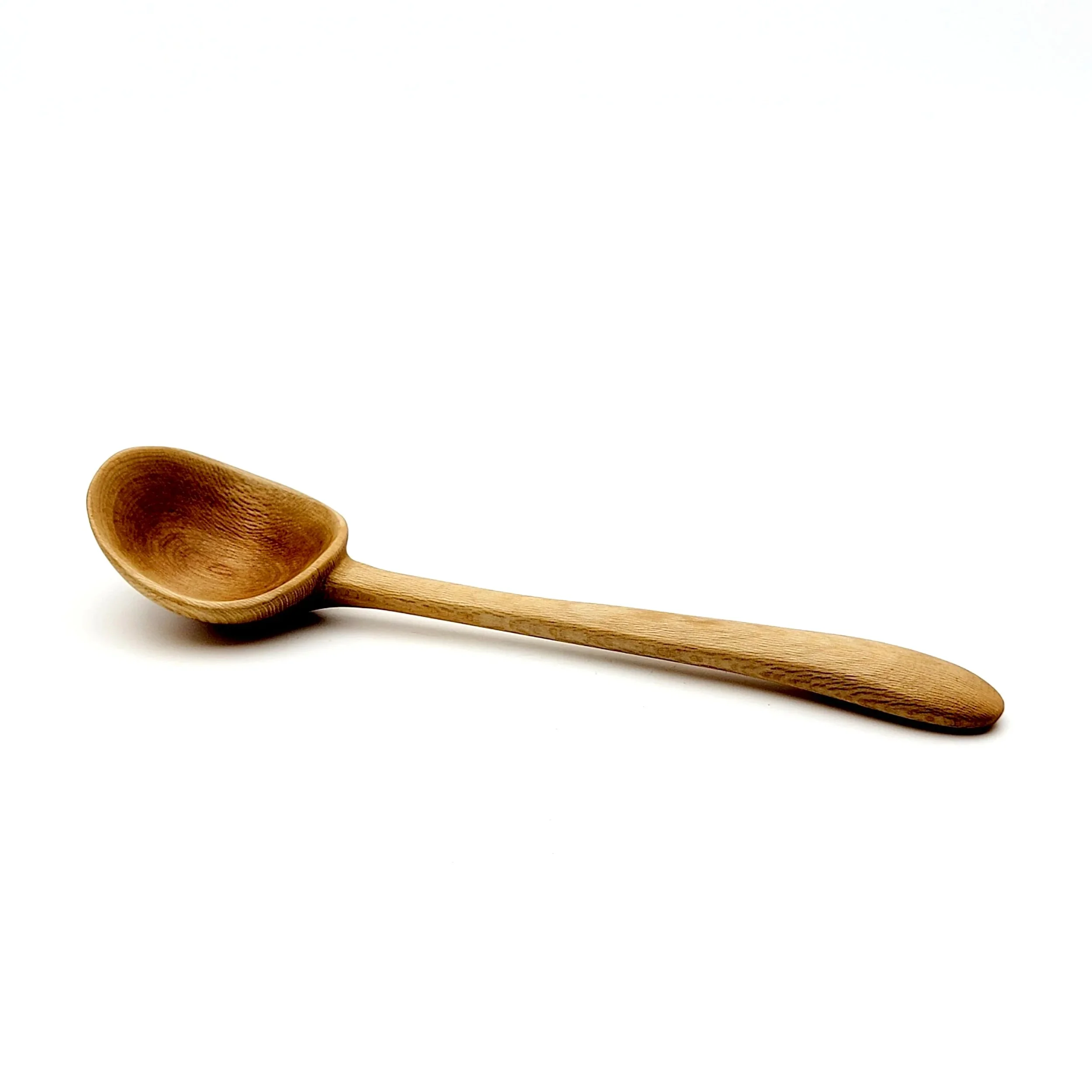 A wooden spoon with a rounded bowl and a long handle, lying on a white surface.