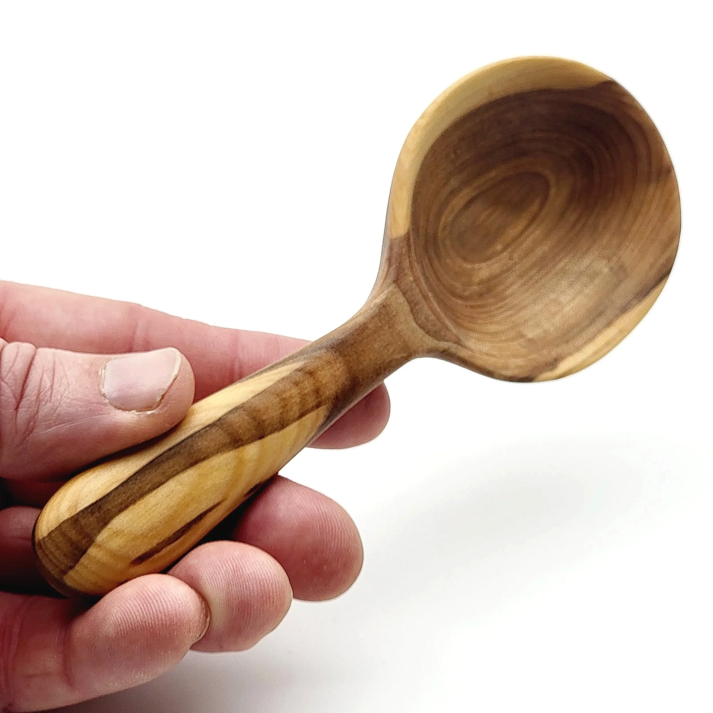 Hand holding a wooden scoop with a rounded bowl and a striped wood grain handle.