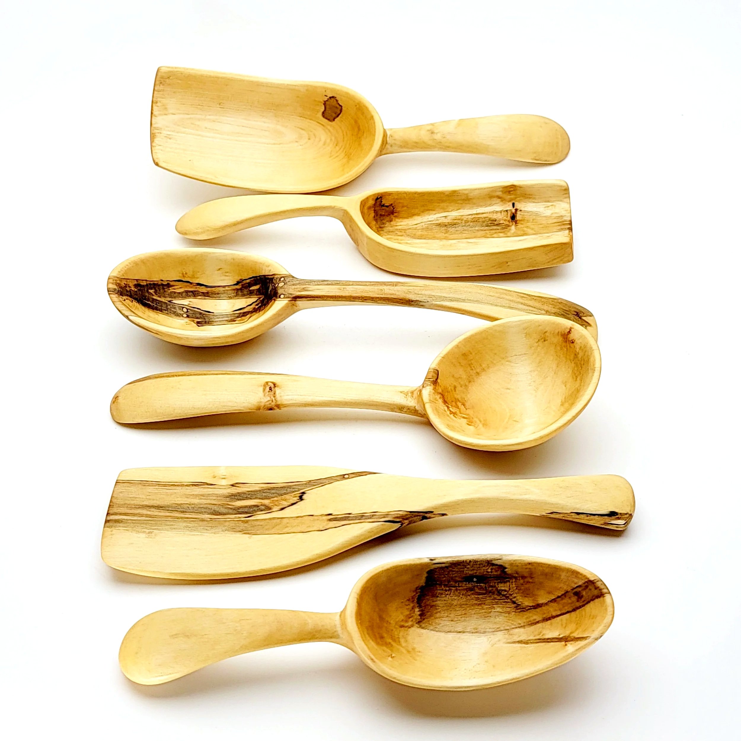 Six wooden scoops arranged horizontally on a white background.