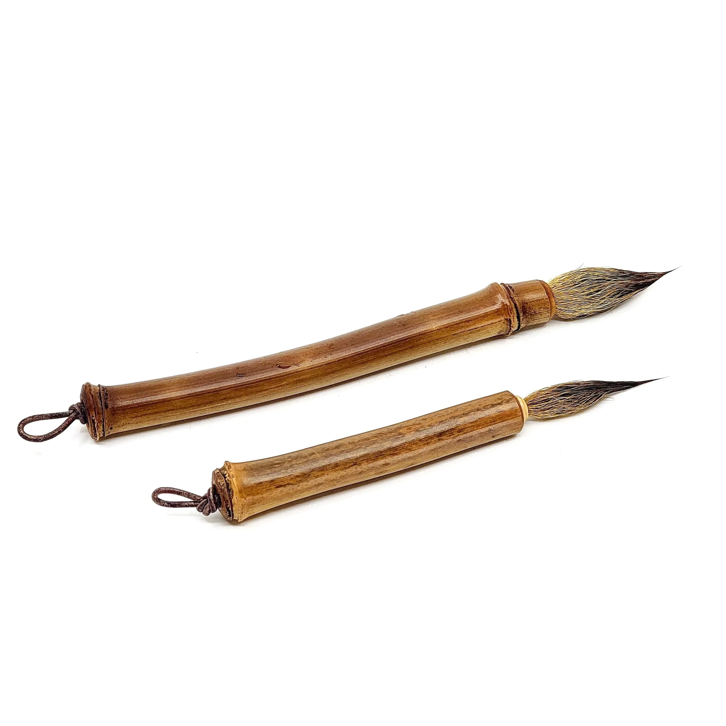 Two traditional calligraphy brushes with bamboo handles and animal hair bristles, laid against a white background.