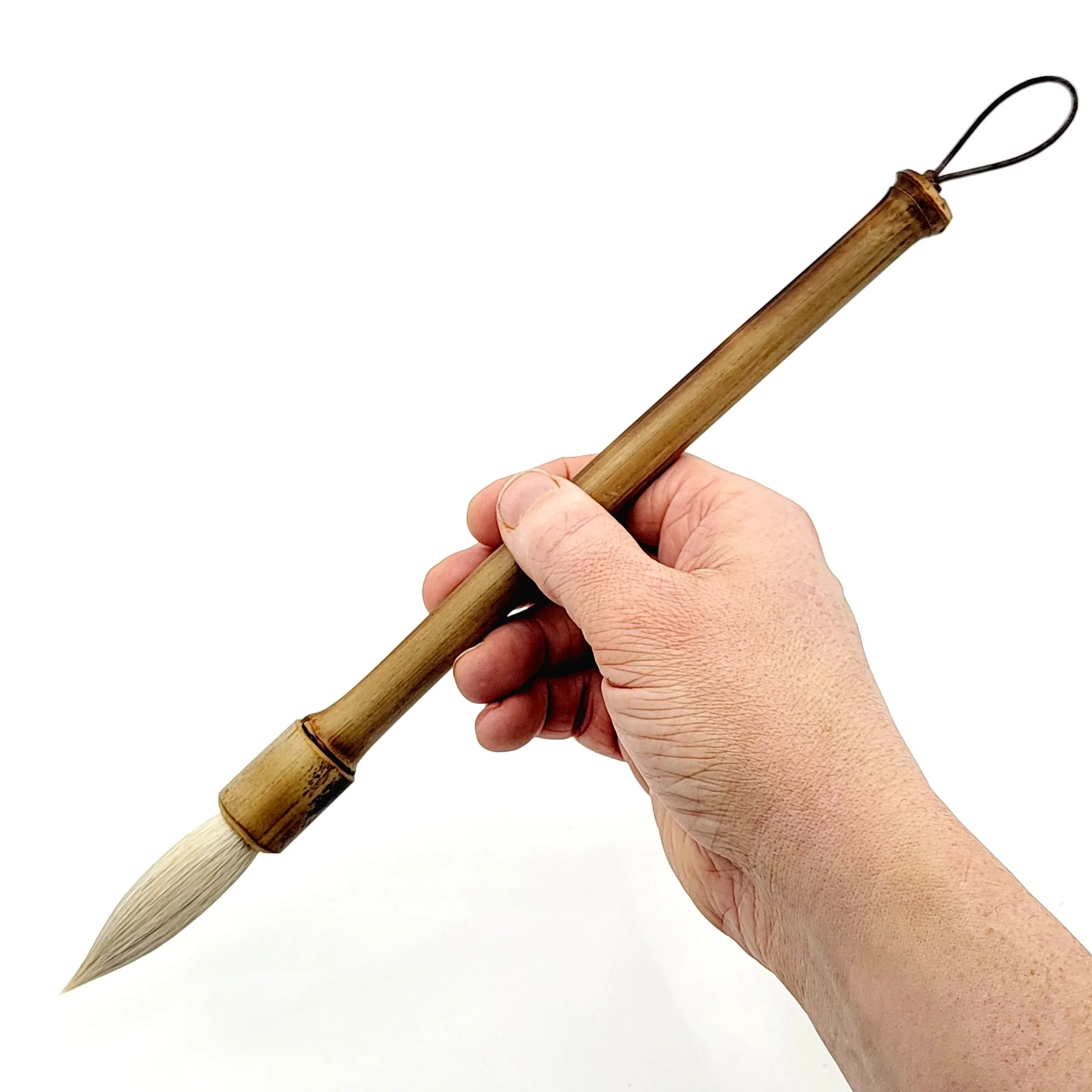 Hand holding a wooden brush with a pointed tip and loop at the end, against a plain white background.