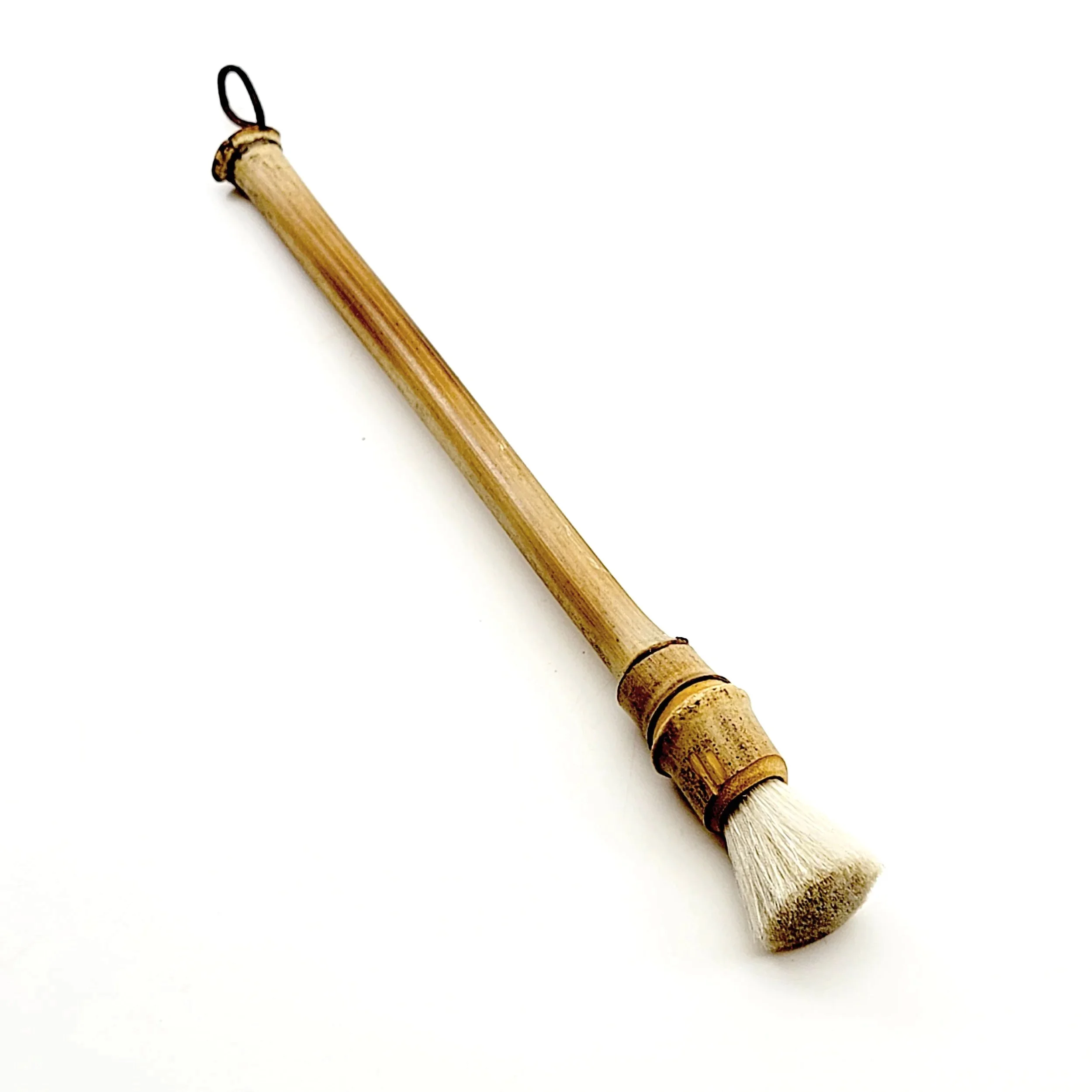 A small paintbrush with a bamboo handle and white bristles resting on a white background.