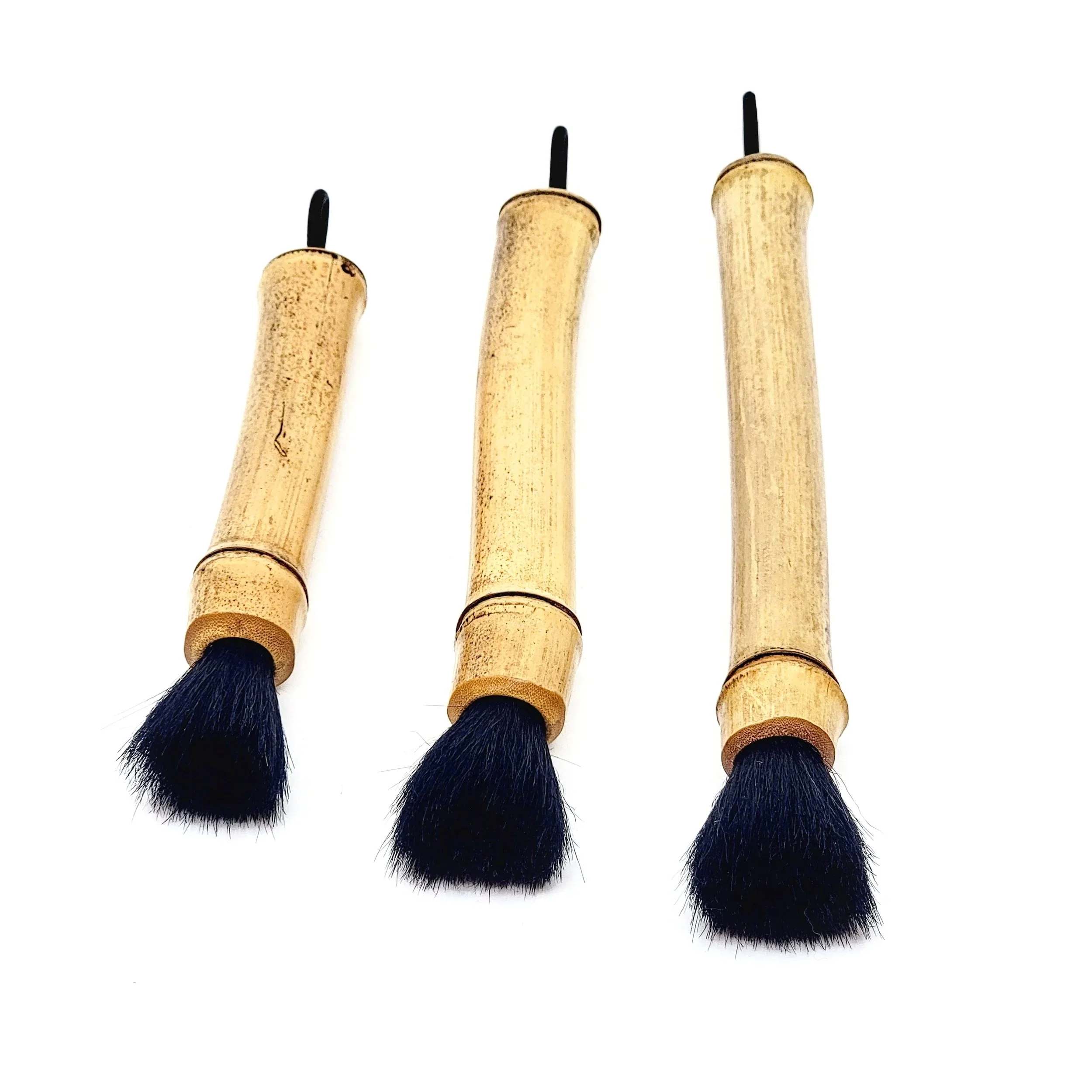 Three makeup brushes with bamboo handles and black bristles, arranged in a row on a white background.