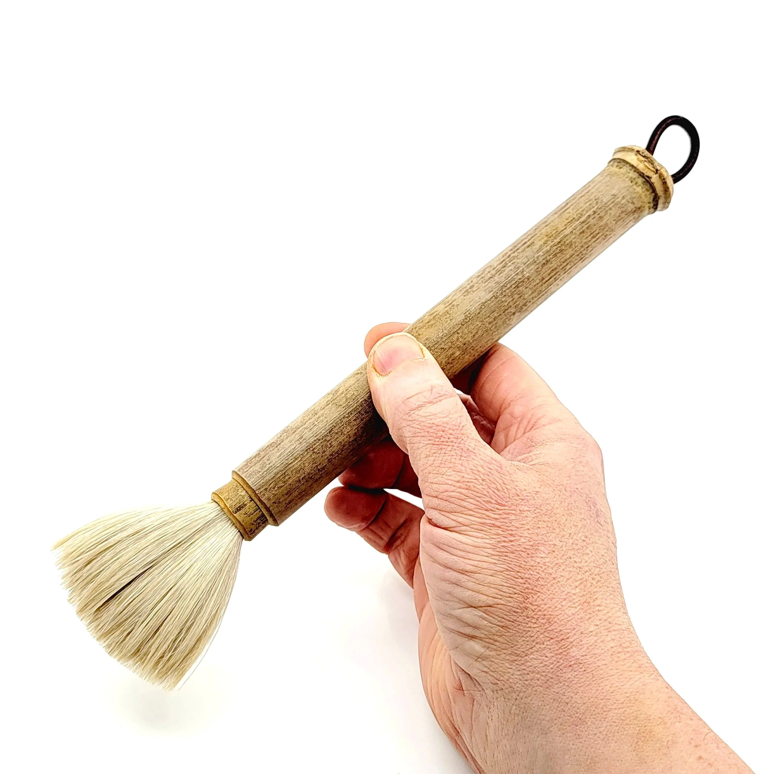 Hand holding a cleaning dusting tool with a wooden handle and natural bristle brush.