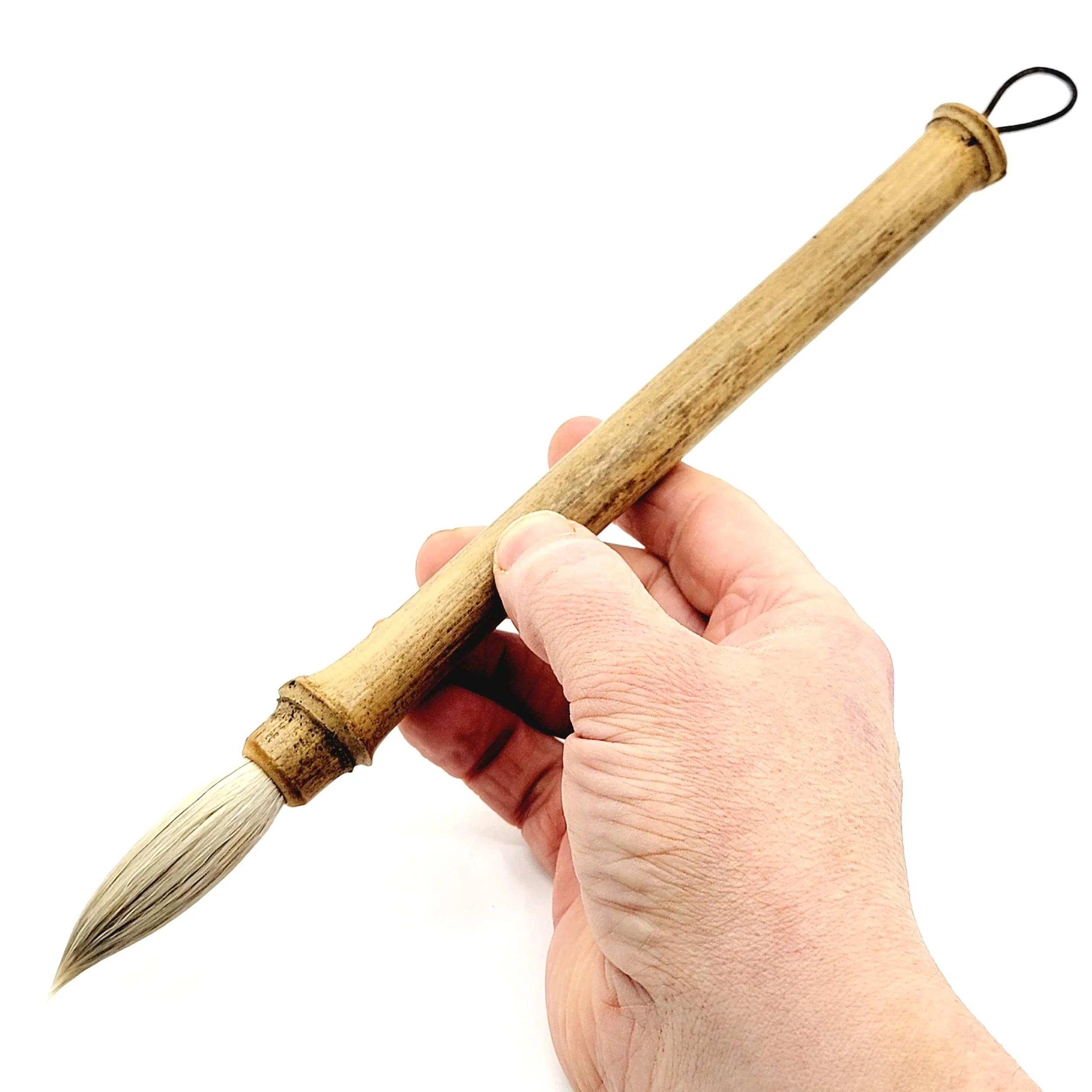 A hand holding a traditional bamboo brush with a wooden handle and natural bristles.