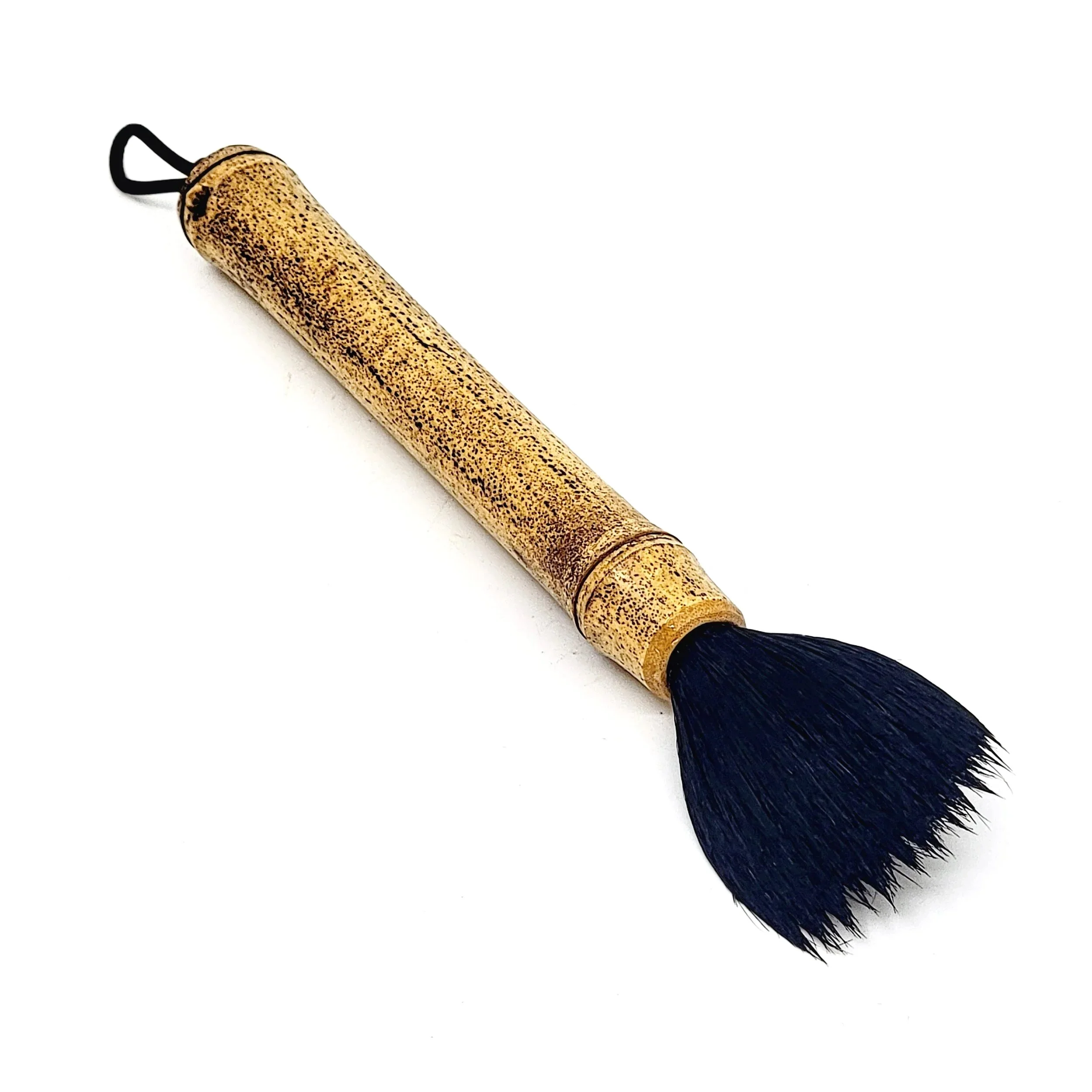 A cosmetic brush with a handle that resembles bamboo and black bristles, positioned diagonally on a white background.