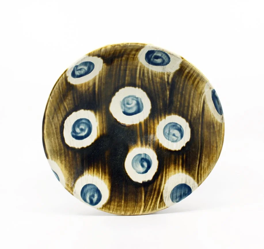 A round, decorative object with black, brown, and white swirled pattern resembling a star or eye designs.