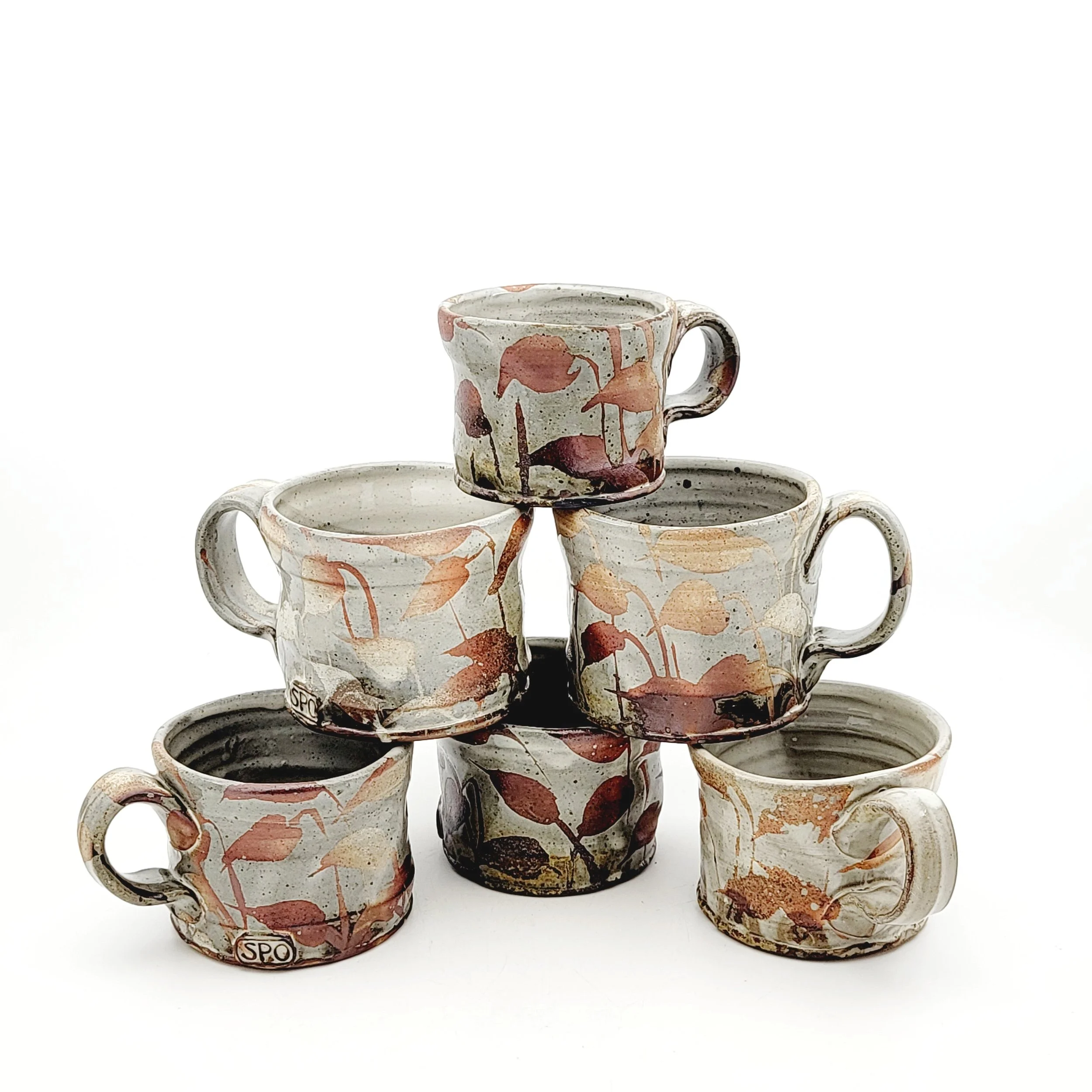 Six ceramic coffee mugs with a floral design in shades of brown, orange, and beige arranged in a pyramid shape against a plain white background.