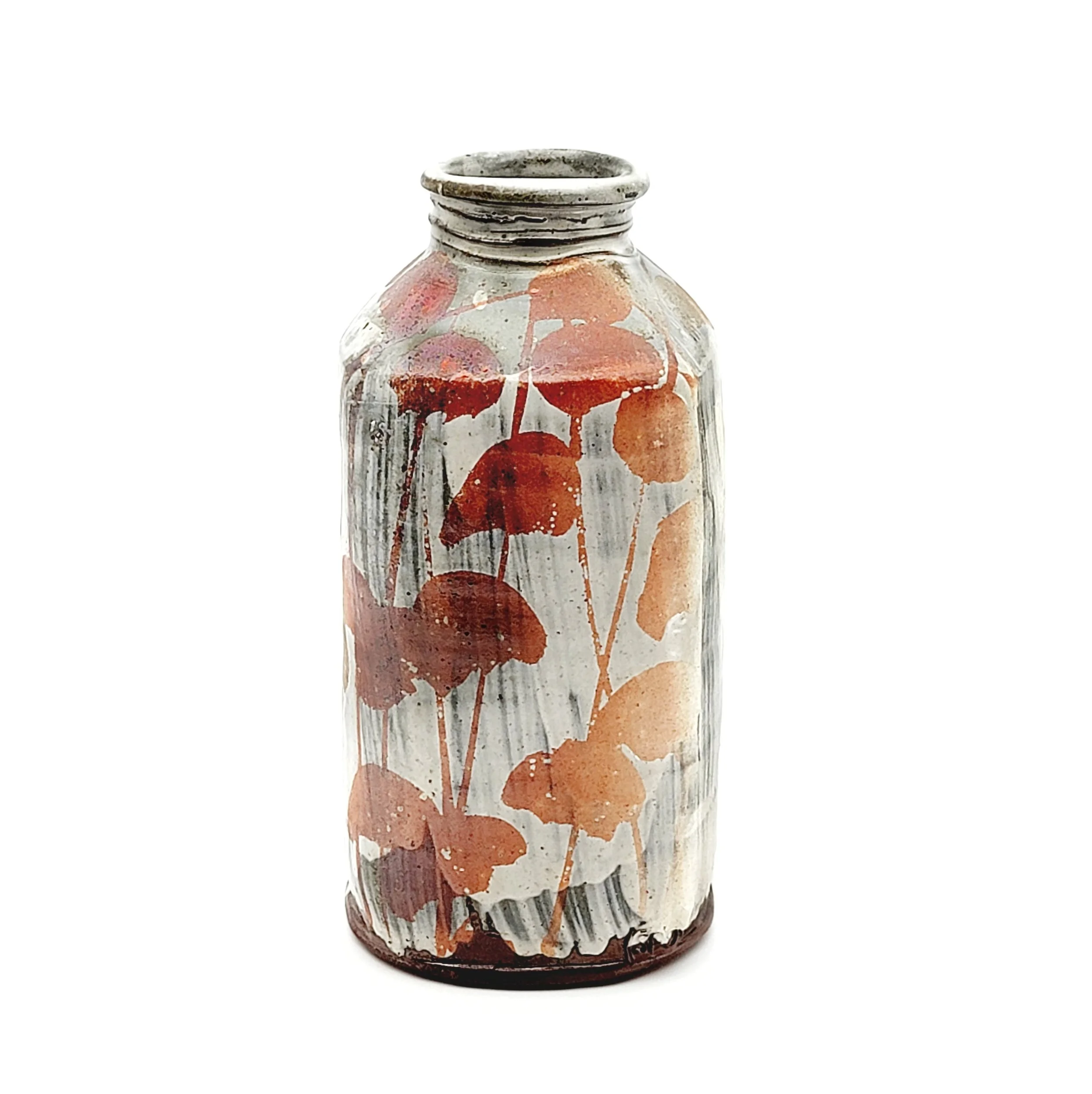 Decorative glass jar with dried orange and red leaves and berries pressed inside
