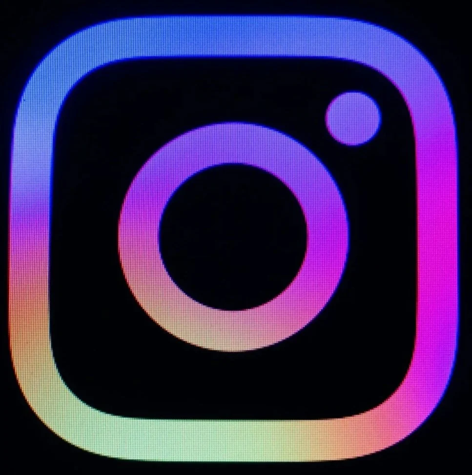 Instagram logo with rainbow gradient on black background.
