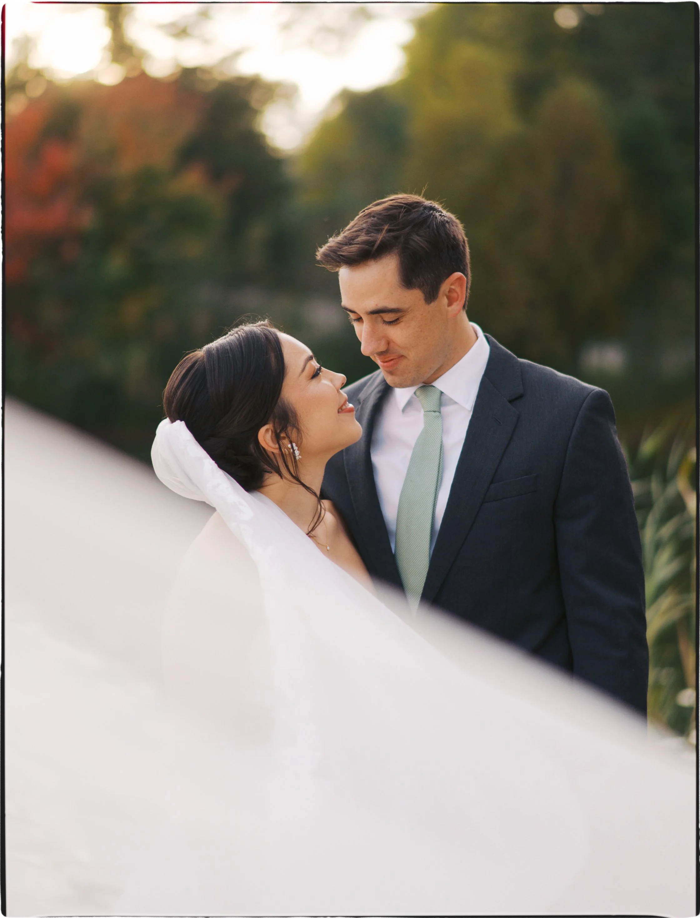 Ottawa Wedding Photo, film wedding, Kodak wedding, 35mm wedding A smiling bride and groom looking at each other outdoors during sunset with trees in the background.