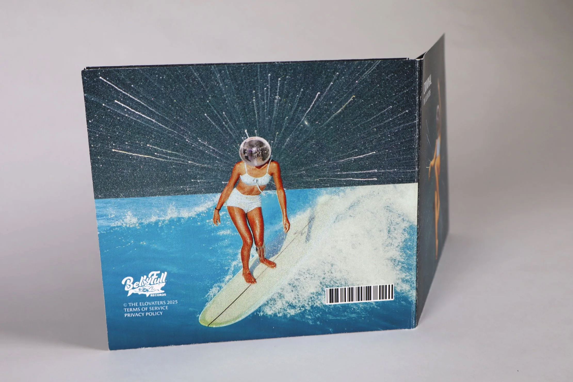 A cardboard box featuring an illustration of a woman in a bikini surfing on a wave with a starry sky and a disco ball as her head.