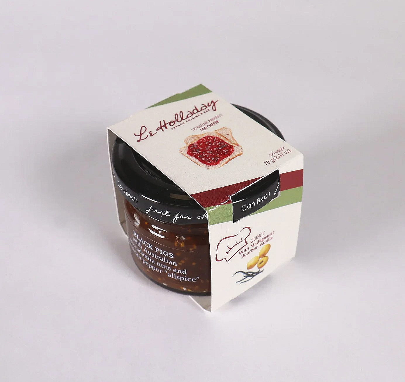 A small jar of Black Figs jam with a paper label that has an illustration of figs and text, enclosed in a paper sleeve with the brand 'Le Holladay' and a picture of bread with jam on top.