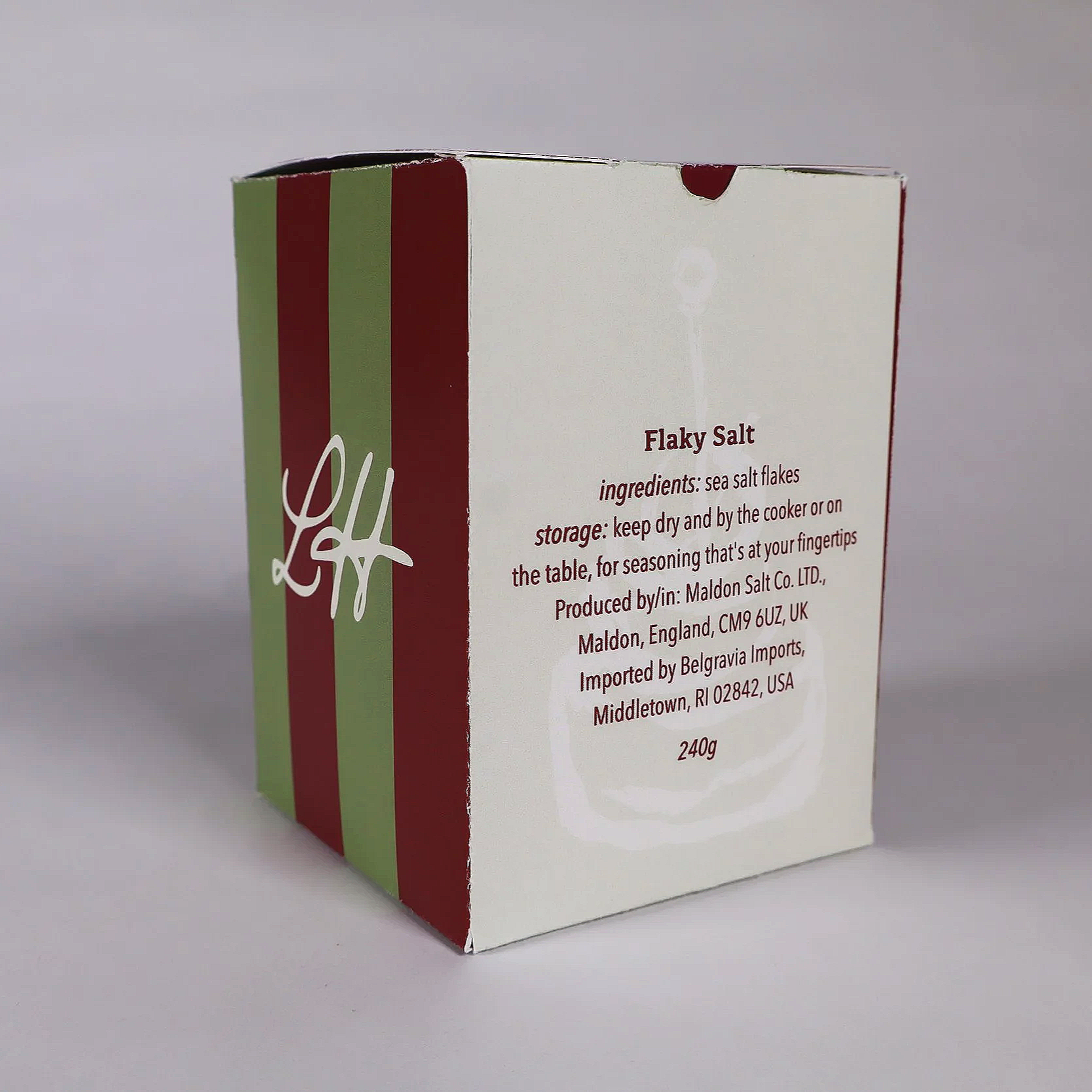 A white and red box of flaky sea salt with green vertical stripes on the side, displaying ingredient and storage information, produced by Maldon Salt Co. LTD.