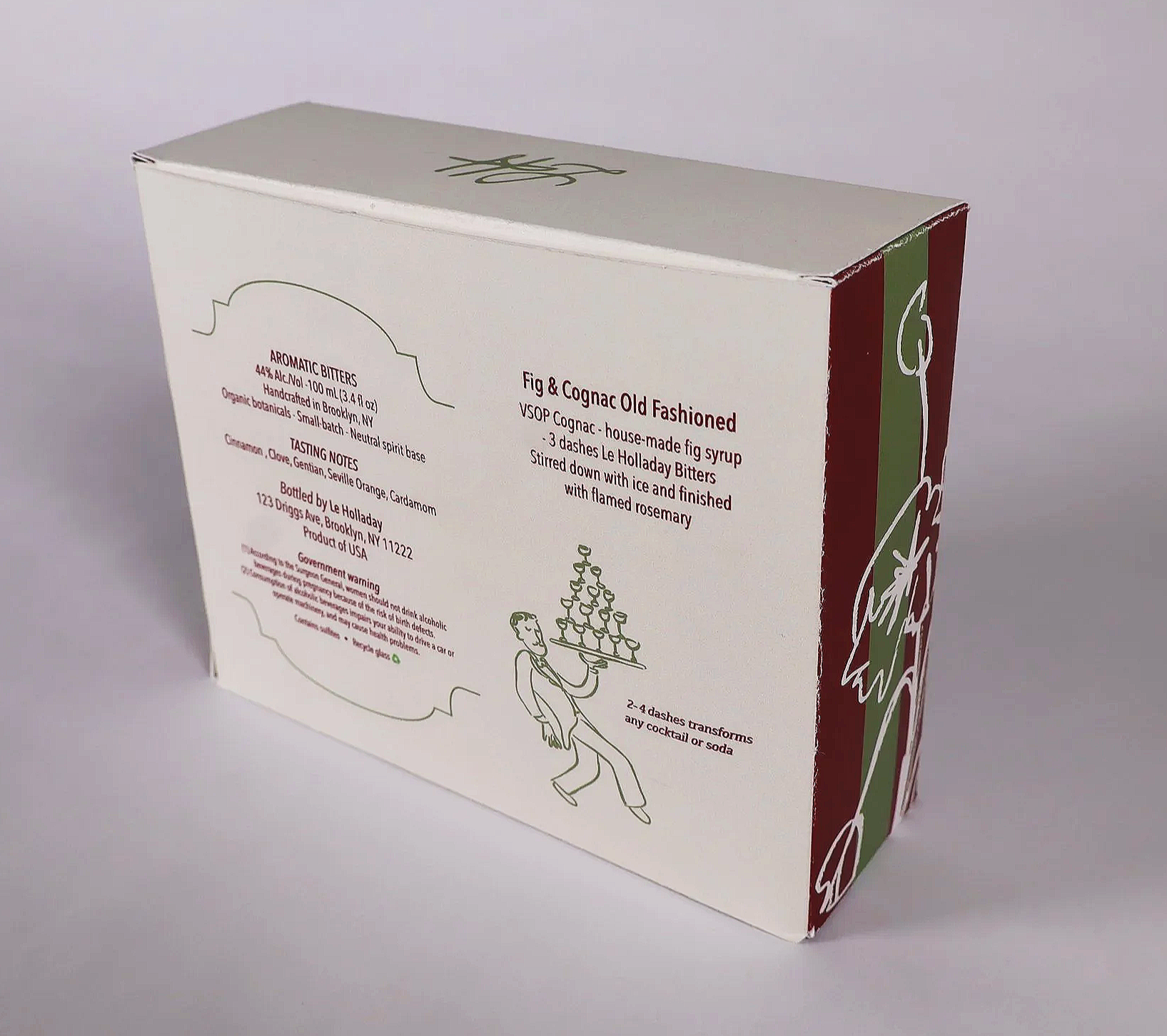Box with a white background and red, green, and white decorative sides, featuring text about a fig and cognac old fashioned cocktail mix with illustrations of a bartender holding a tray of glasses.