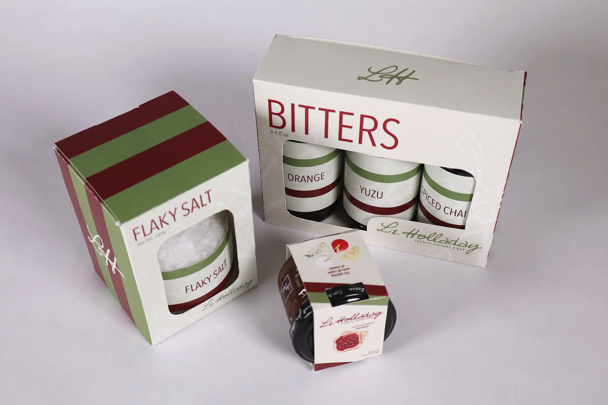 Set of three spice jars labeled orange, yuzu, and spiced chai, along with a jar of flaky salt and a jar of red ingredient, all in holiday-themed packaging.