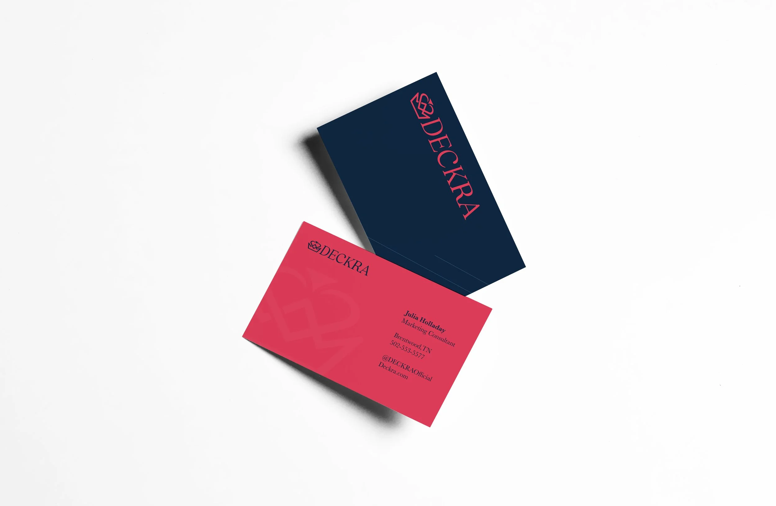 Pink and dark blue business cards with 'DECKRA' logo, placed on a white surface.