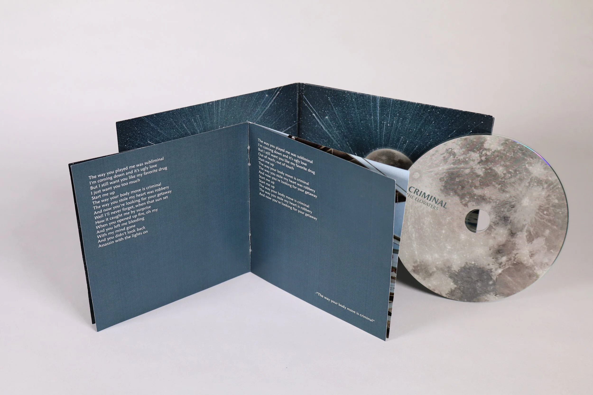 Open CD case displaying the album titled 'Criminal' by The Elovators, with the CD removed and placed next to the case. The inside of the case features dark space-themed visuals and lyrics printed on the left panel.