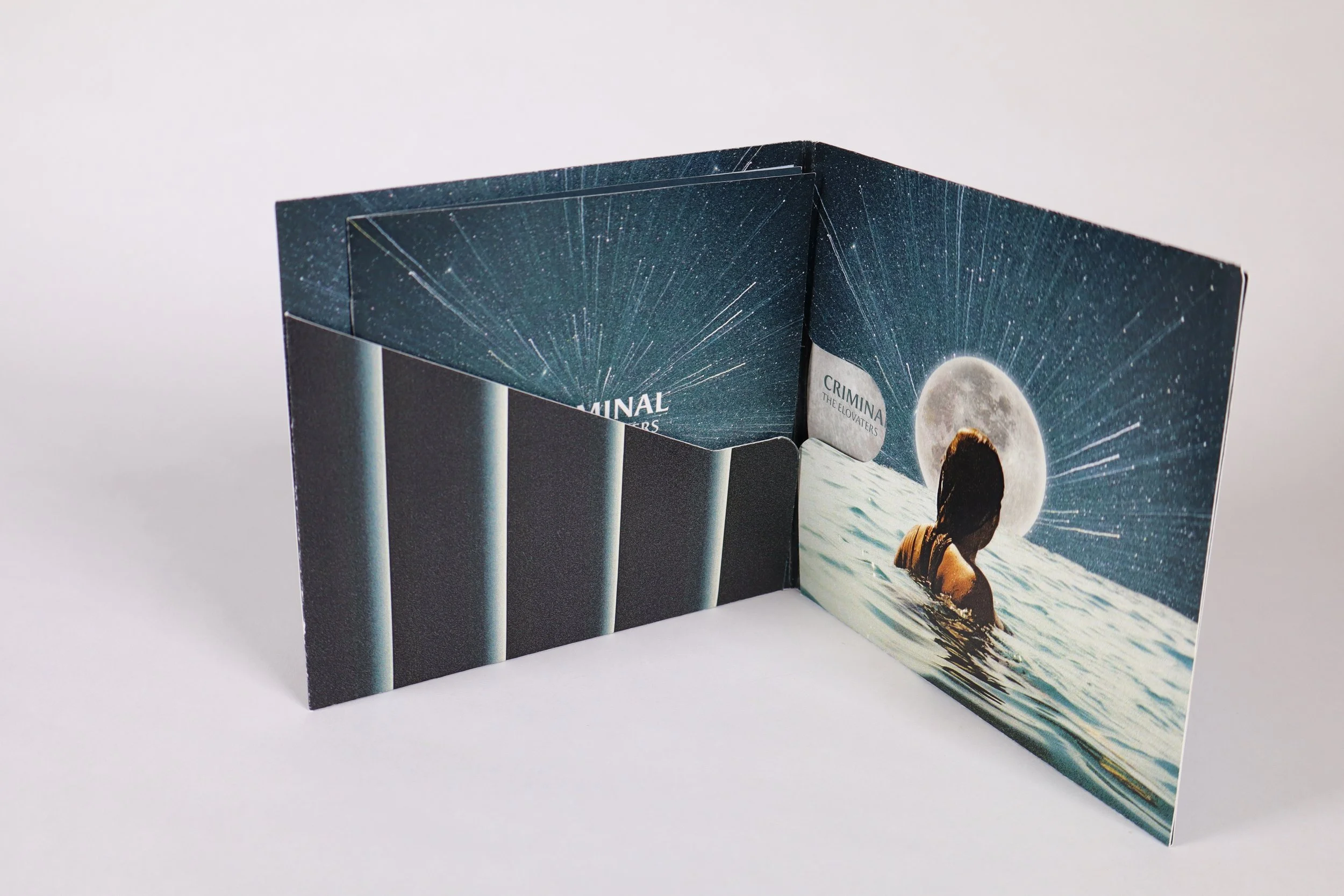 A folded cardboard standee featuring a woman swimming at night with a full moon above and the starry sky, with a design resembling a star explosion in the background.