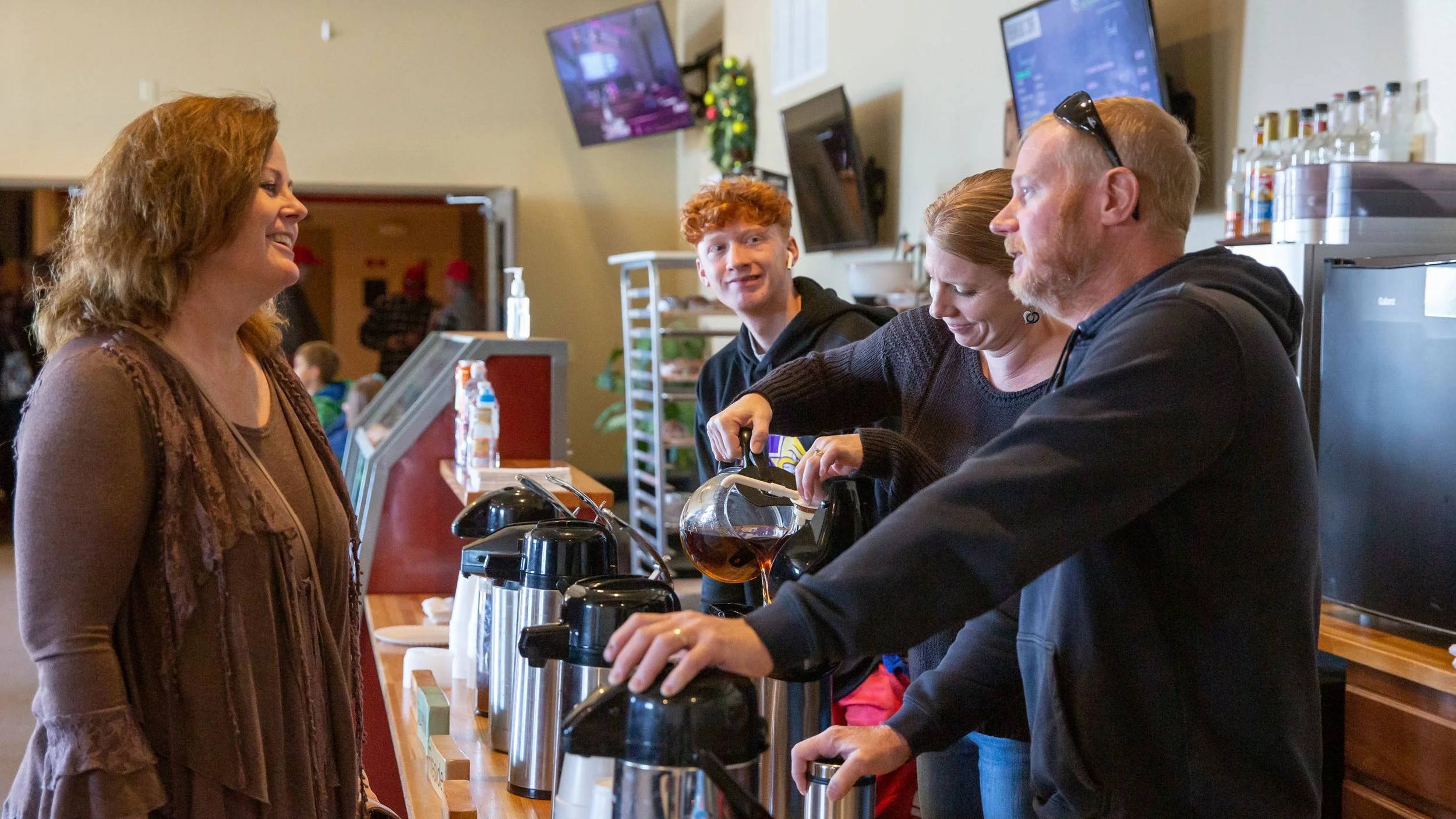 People serving and ordering coffee or tea at a counter in a cafe or restaurant.