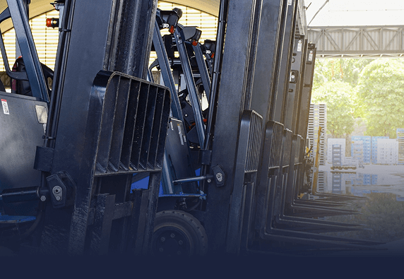 Row of forklifts parked inside a warehouse or industrial space.