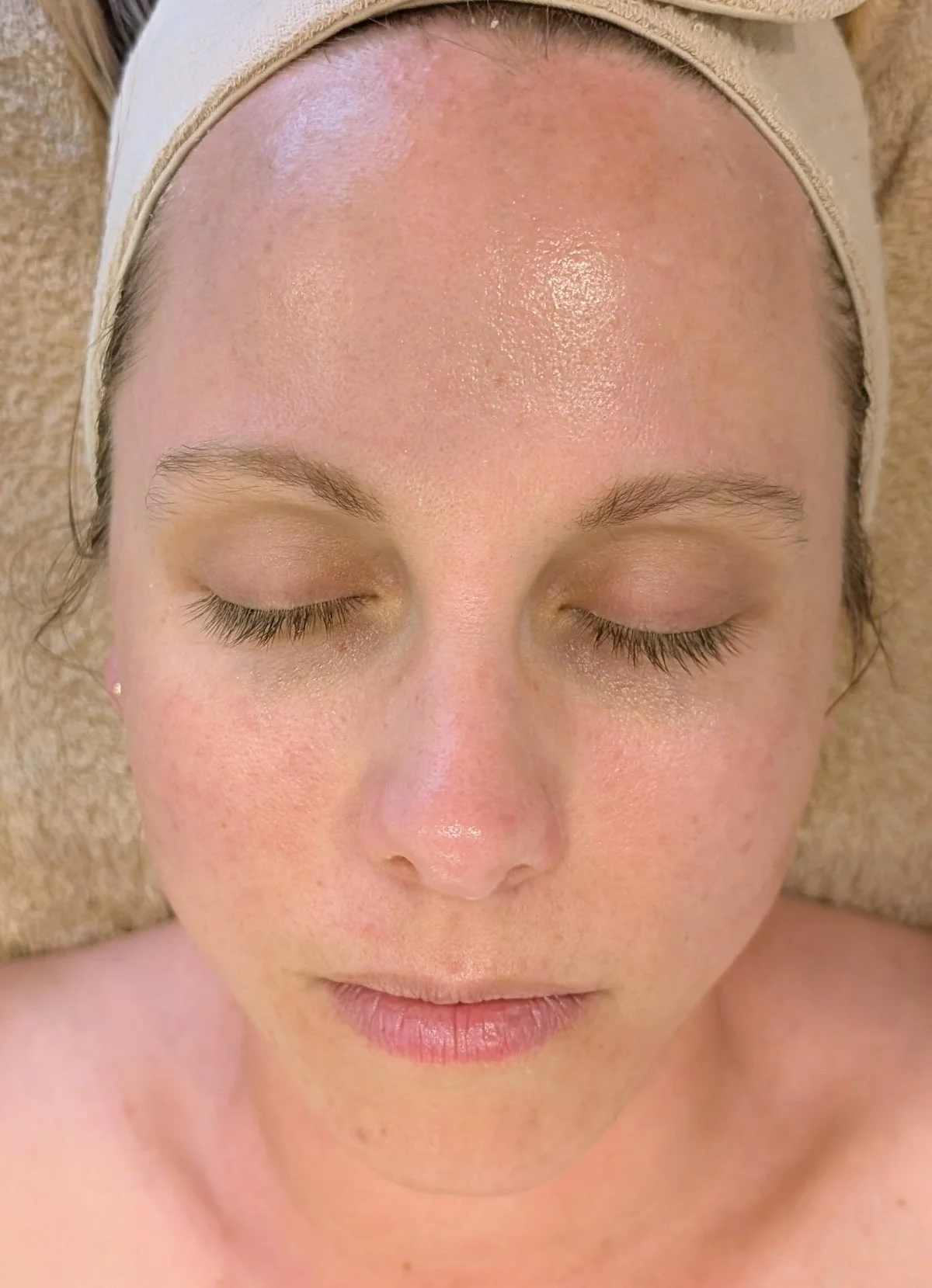 Close-up of a woman's face with closed eyes, wearing a headband, showing her forehead, eyebrows, eyelashes, and closed lips.