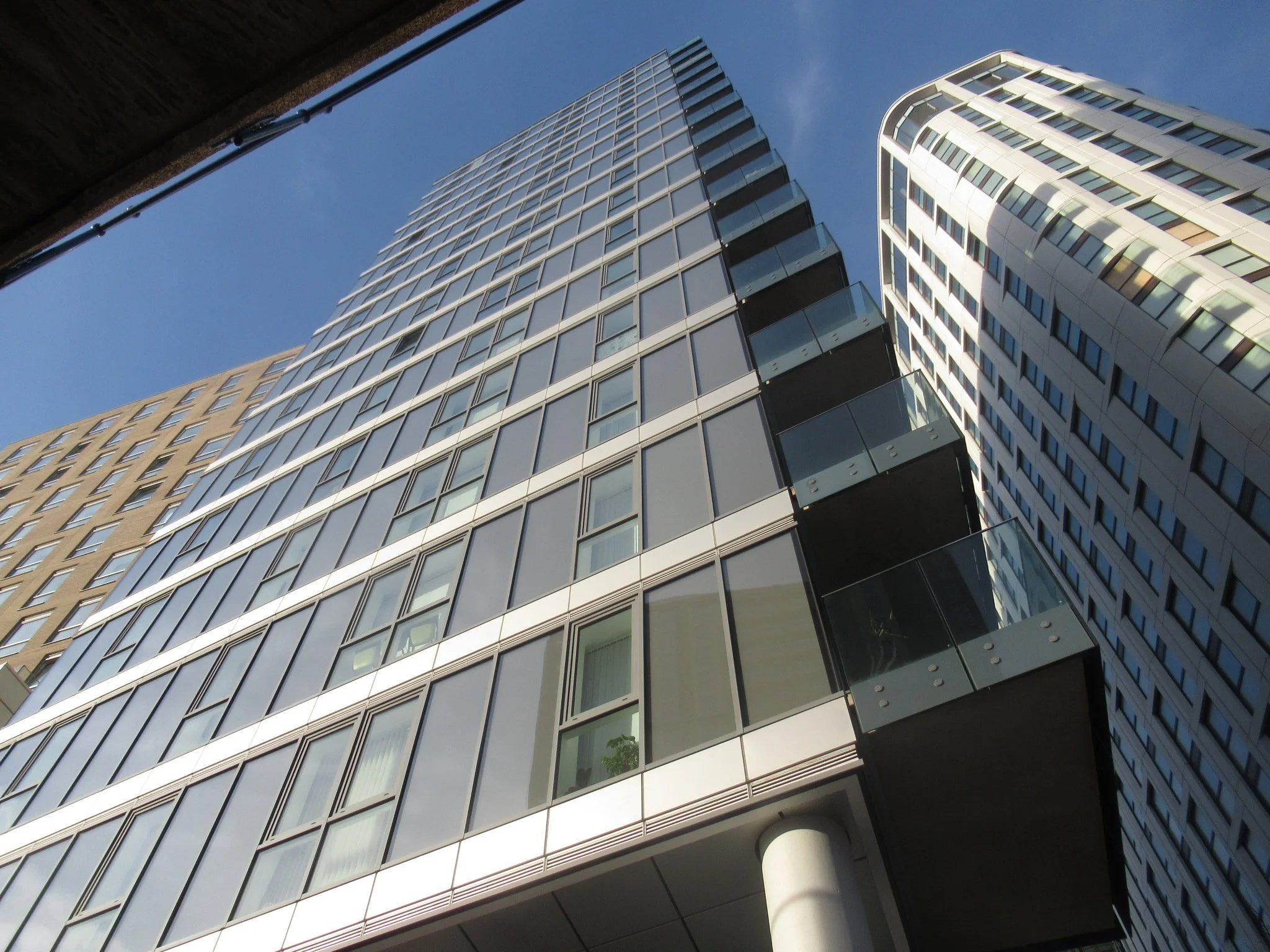 Low-angle shot of modern glass and steel high-rise buildings against a blue sky.