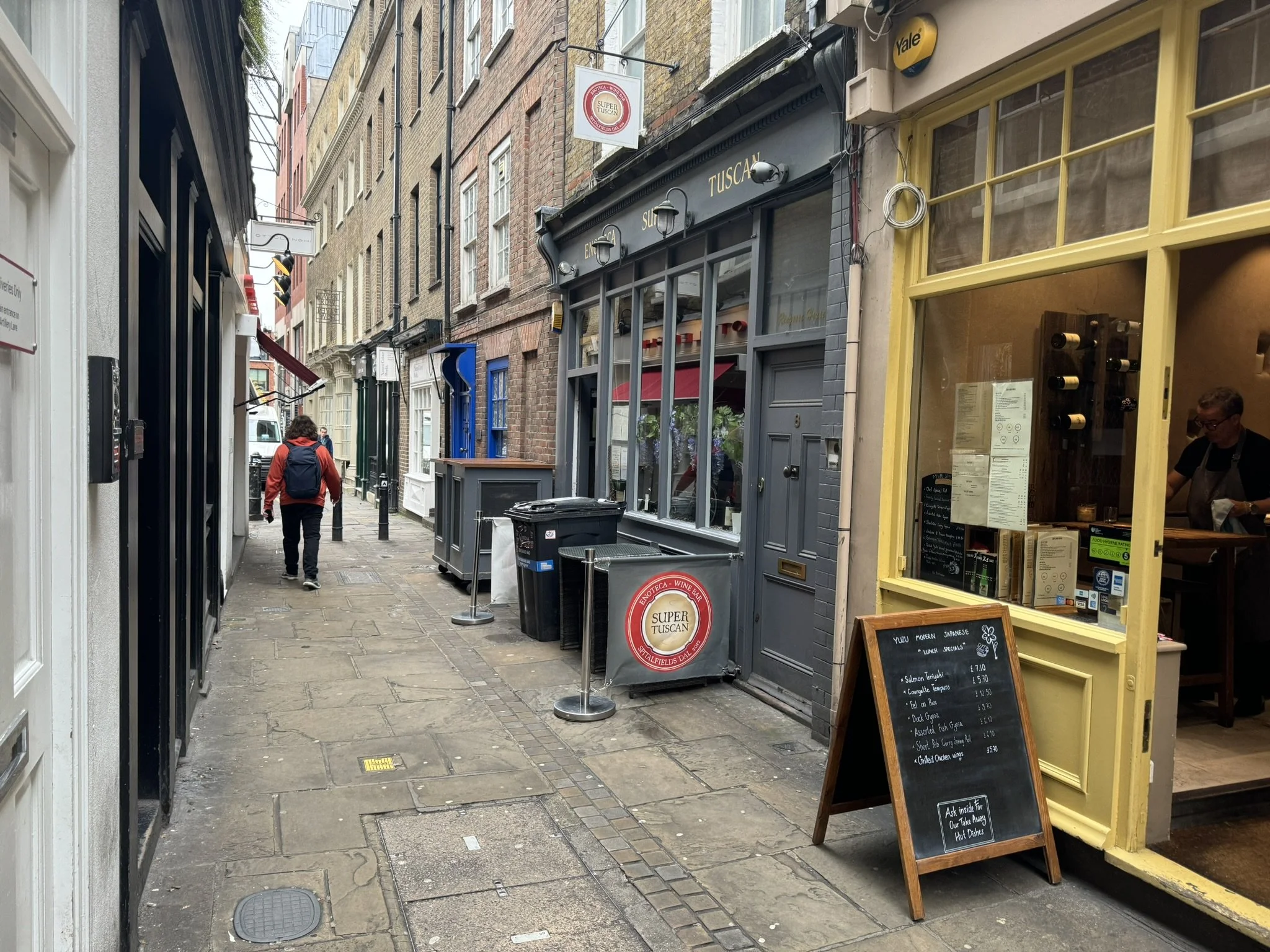 A modern poolside area with white lounge chairs, desert plants, and a beige house with a patio, trees, and outdoor furniture.
