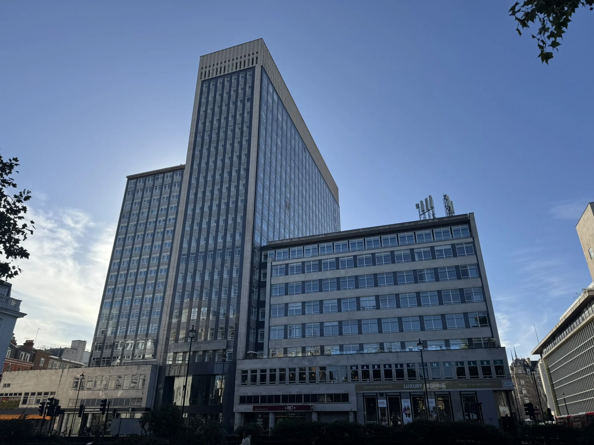 Tall modern glass and concrete office buildings in an urban area with a clear blue sky overhead.