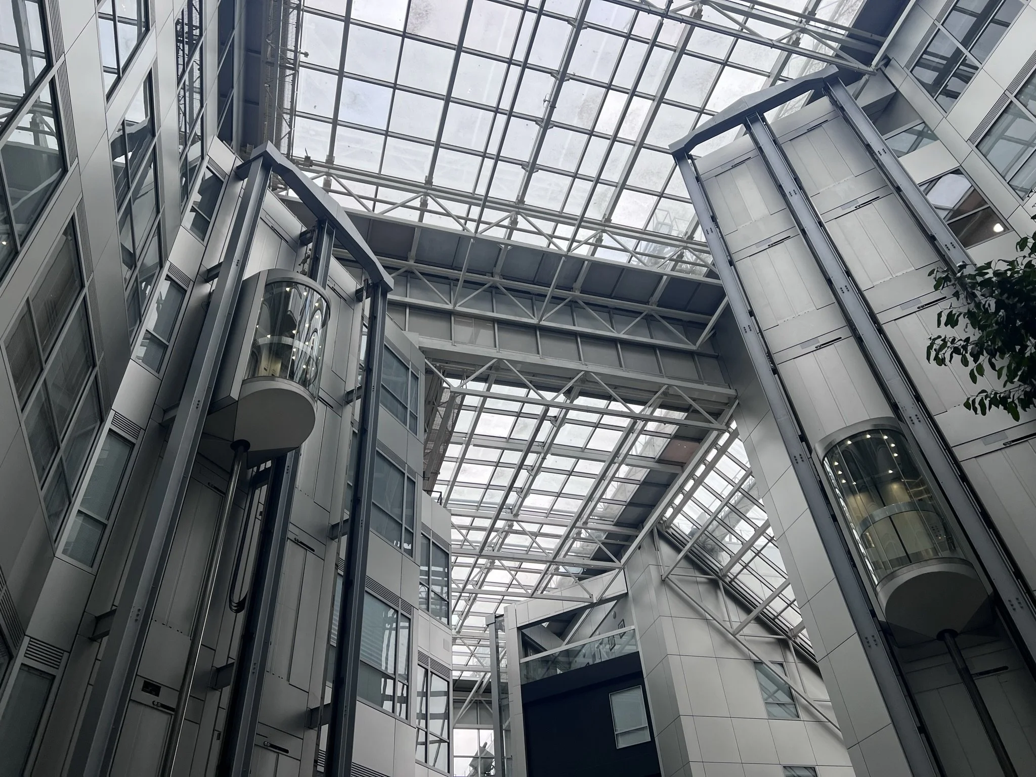 Interior view of a modern building with glass elevators and a glass ceiling.