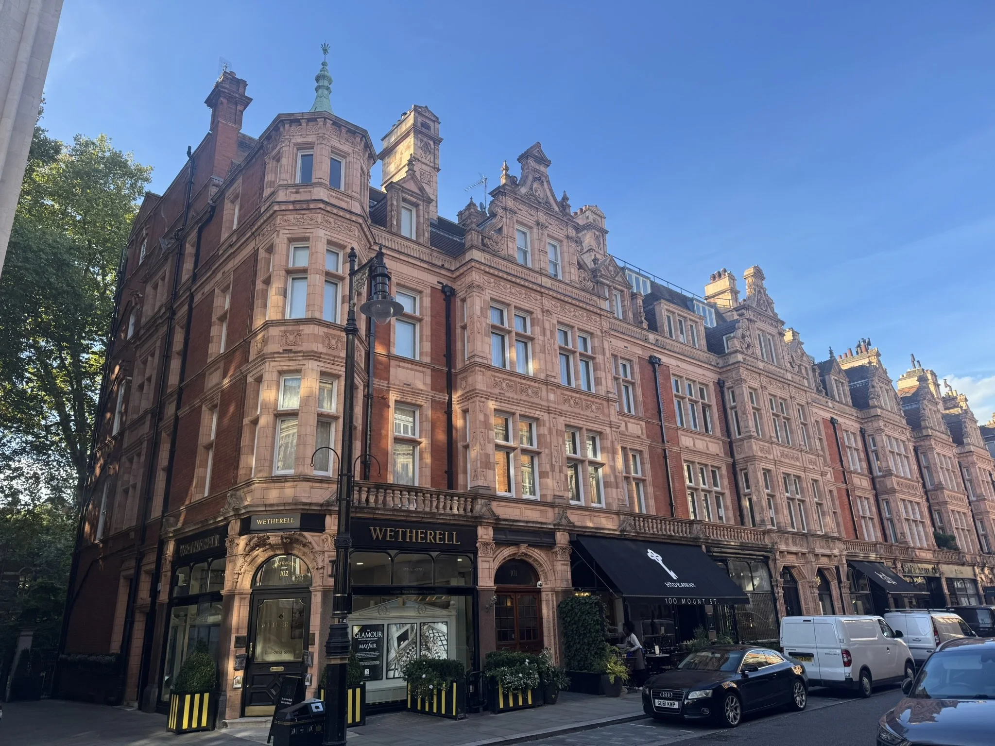 Close-up of a sandy beach with clear shallow water, showing intricate patterns of ripples and a few small pebbles.