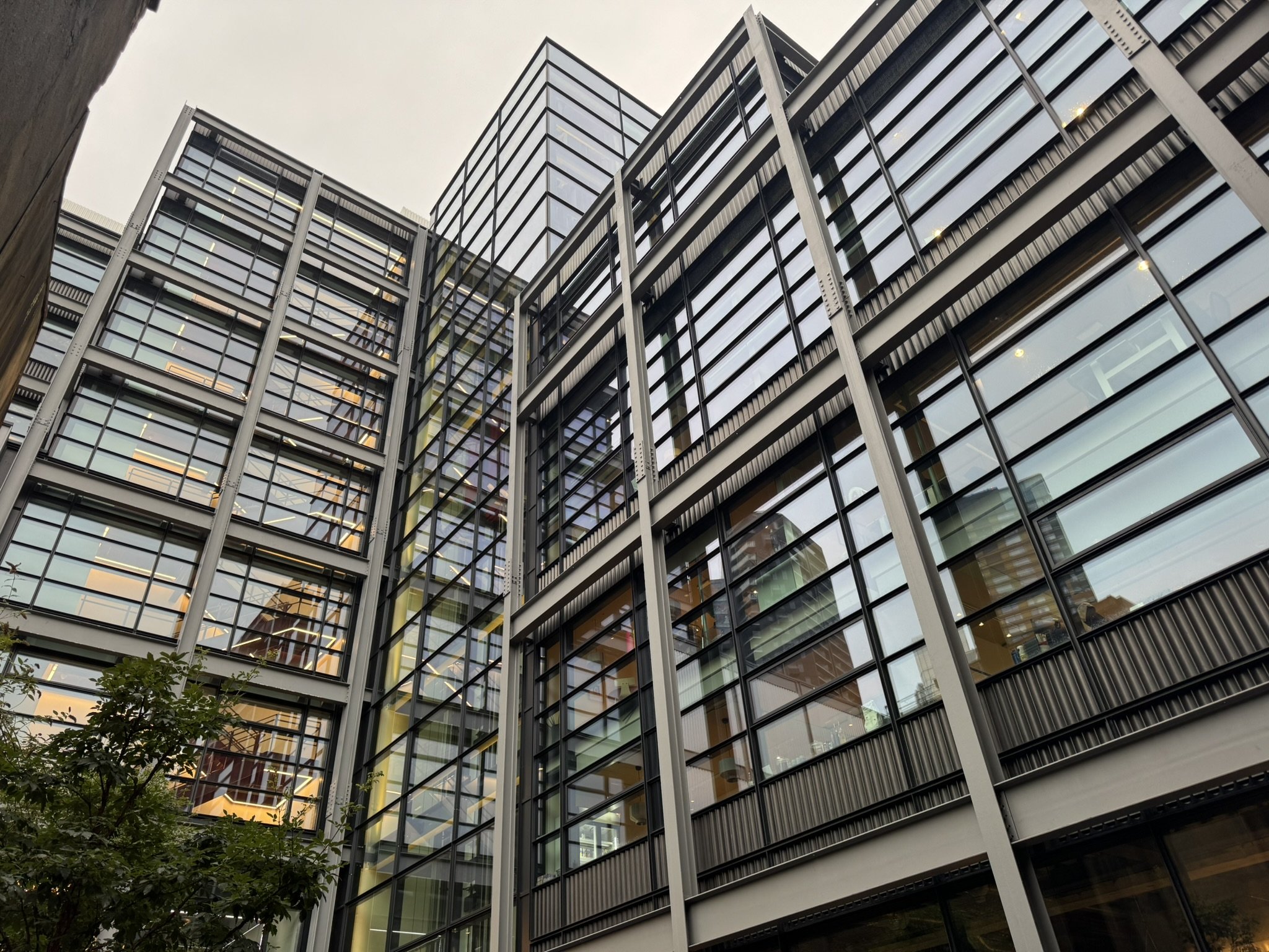 Low-angle view of a modern glass office building with reflective windows and metal framing at dusk.
