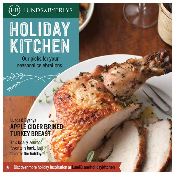A plate with cooked turkey breast, garnished with herbs, on a wooden table with a fork. There is a glass of wine and a bowl in the background. The image promotes Lunds & Byerlys Holiday Kitchen, featuring apple cider-brined turkey breast for seasonal
