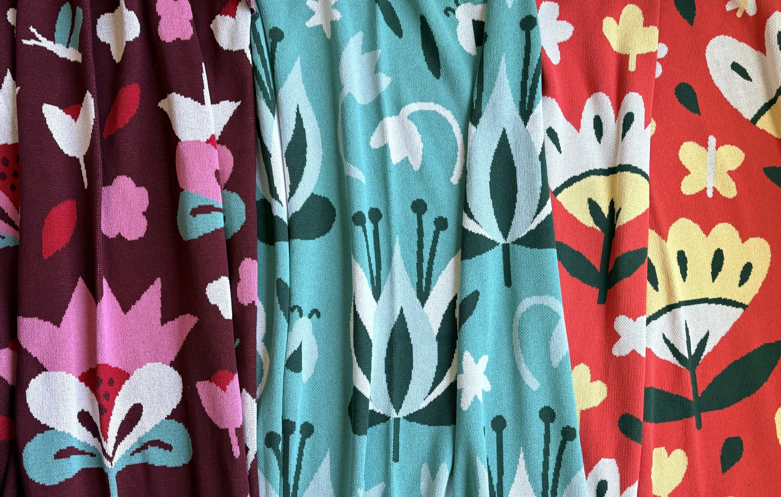Three folk art flower knit blankets made in the USA with recycled cotton.  Each design features unique flowers in vibrant colors featuring little bugs and leaves.