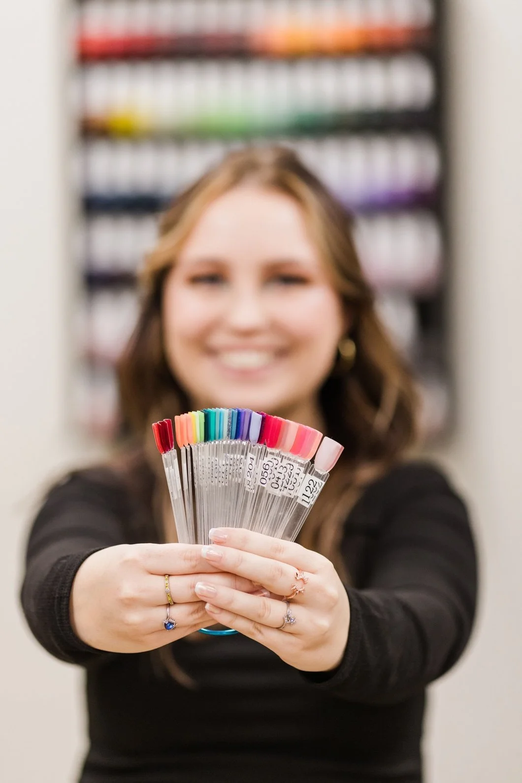 A woman holding a fan of colorful paint swatches in front of her