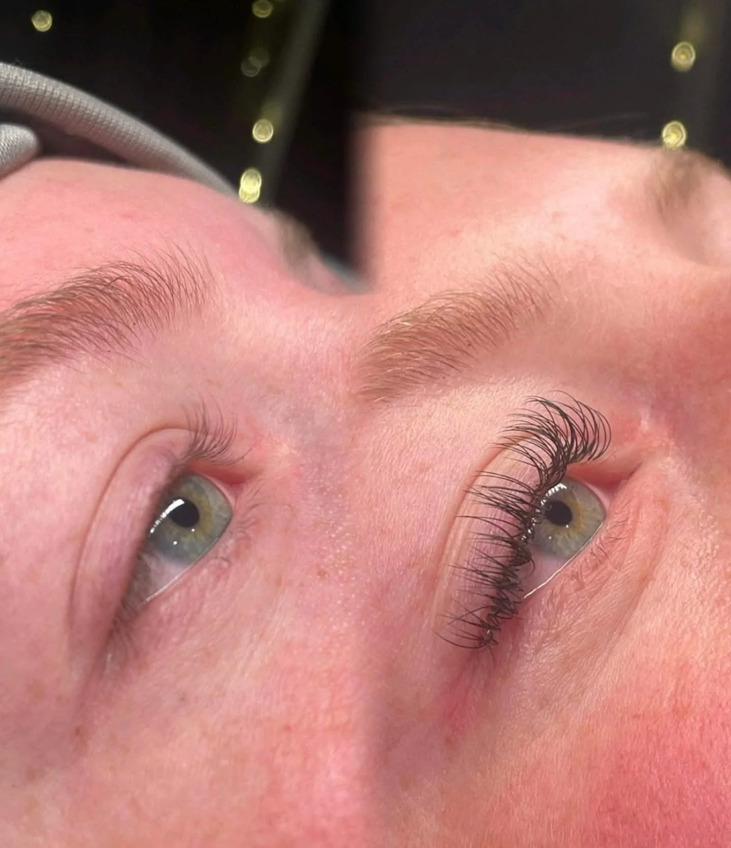 Close-up of a person with newly applied eyelash extensions on one eye, with the other eye natural, showing the difference in eyelash length and curl.