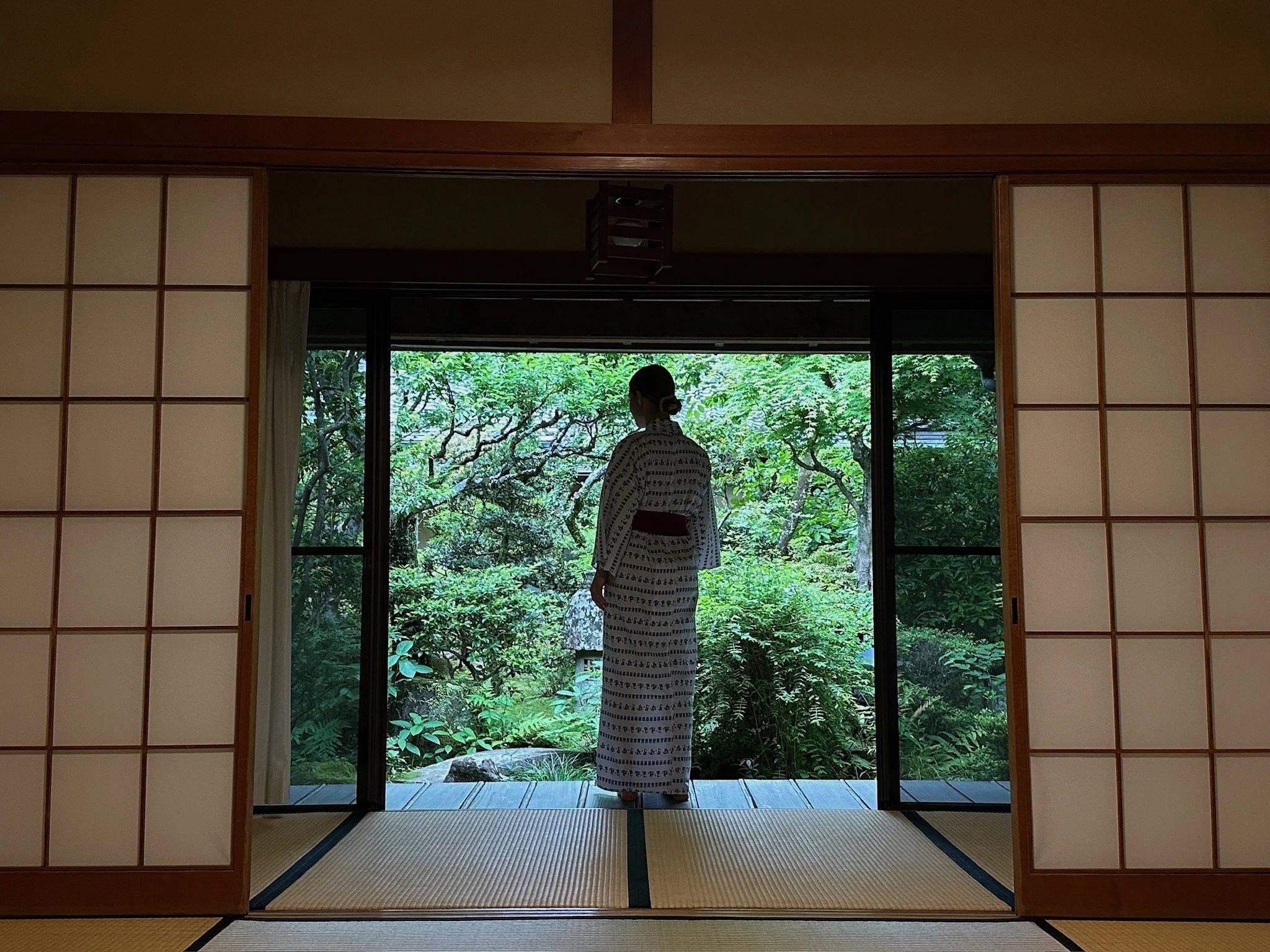 Women in a traditional japanese Ryokan watching into the green garden.