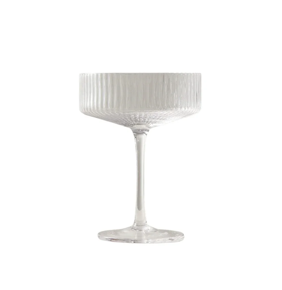 A clear glass coupe with a textured bowl and a long, slender stem, set against a white background.