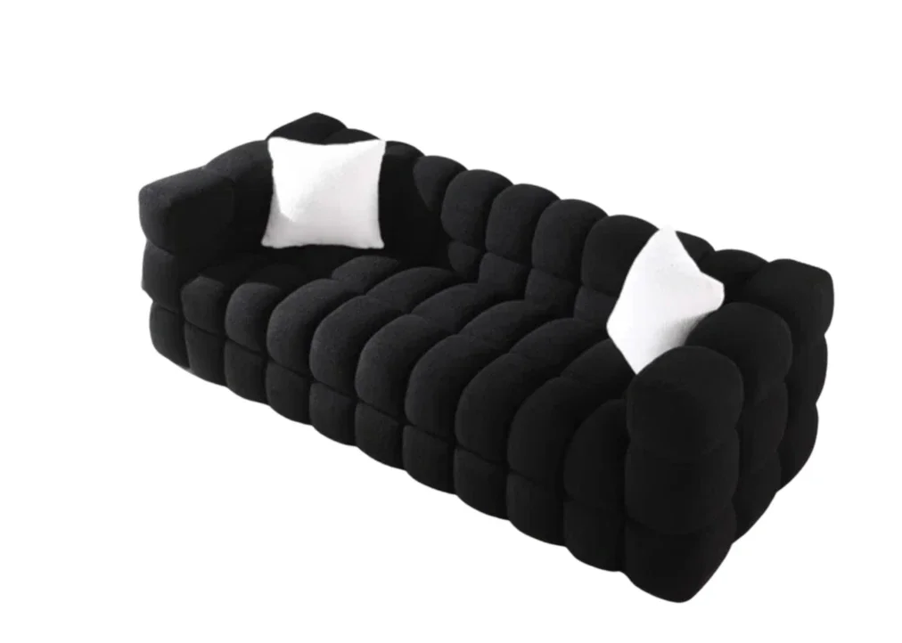 A modern black sofa with a plush, rounded design and two white pillows, set against a white background.
