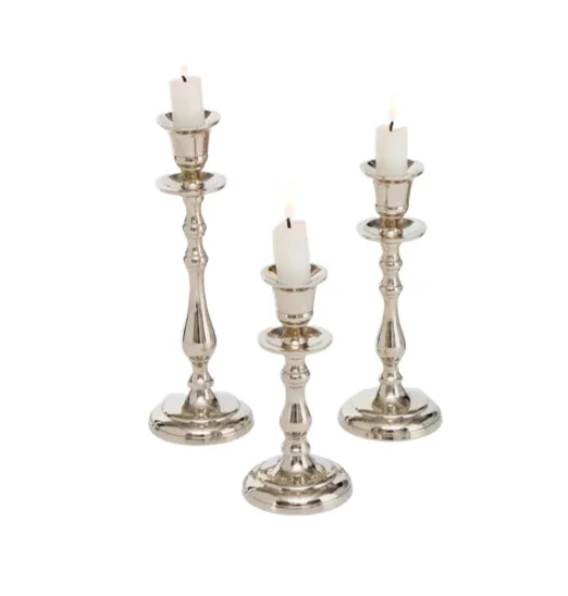 Three silver candlesticks with white candles on top, all lit, arranged in a row.