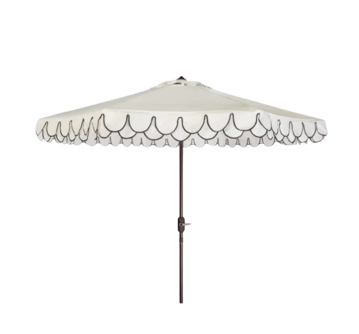A white patio umbrella with scalloped edge design and black trim hanging from the edge, supported by a metal pole.